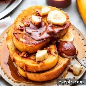 Three slices of French toast are stacked on top of each other on a plate and topped with banana slices and Nutella.