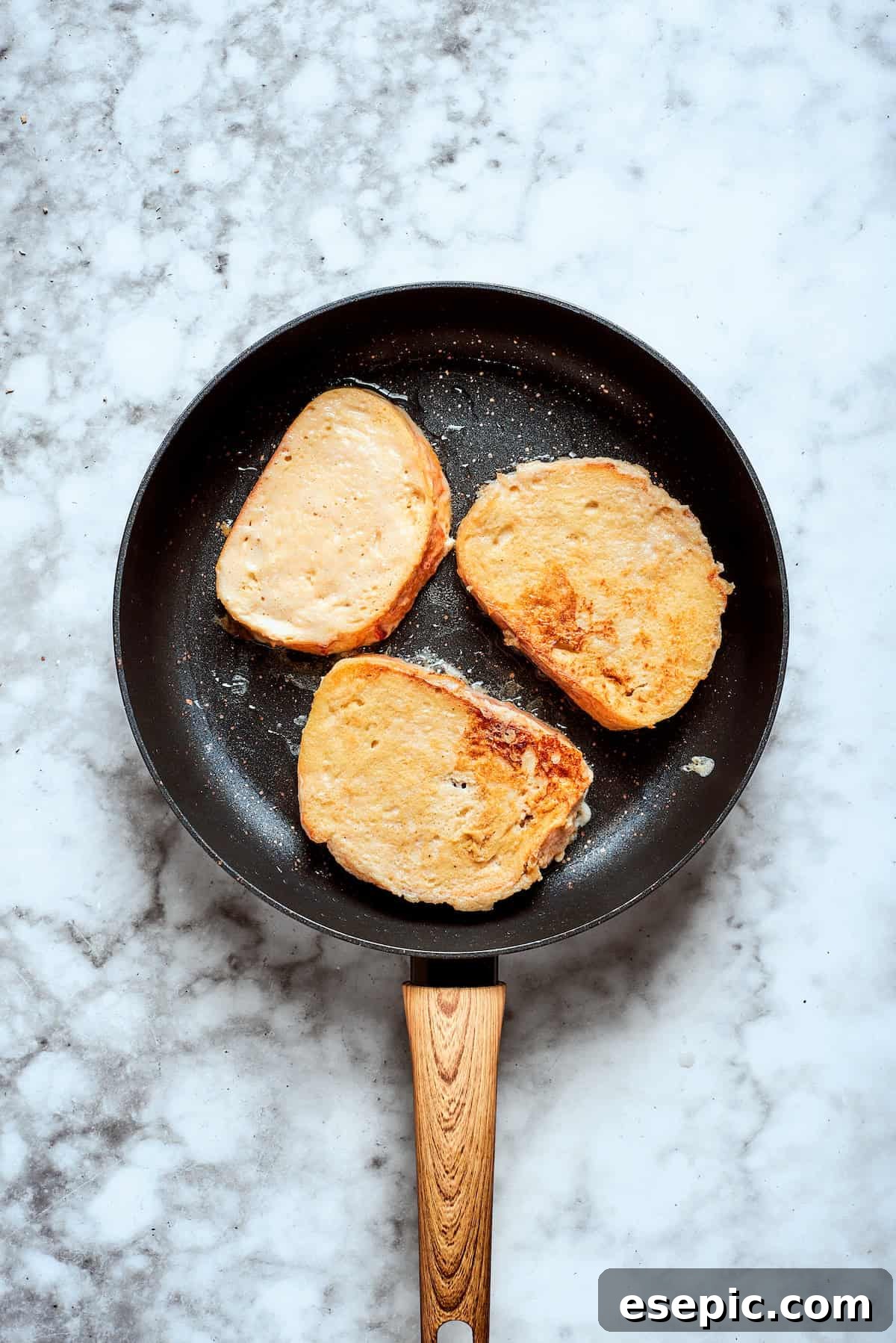 The french toasts fries in a skillet.