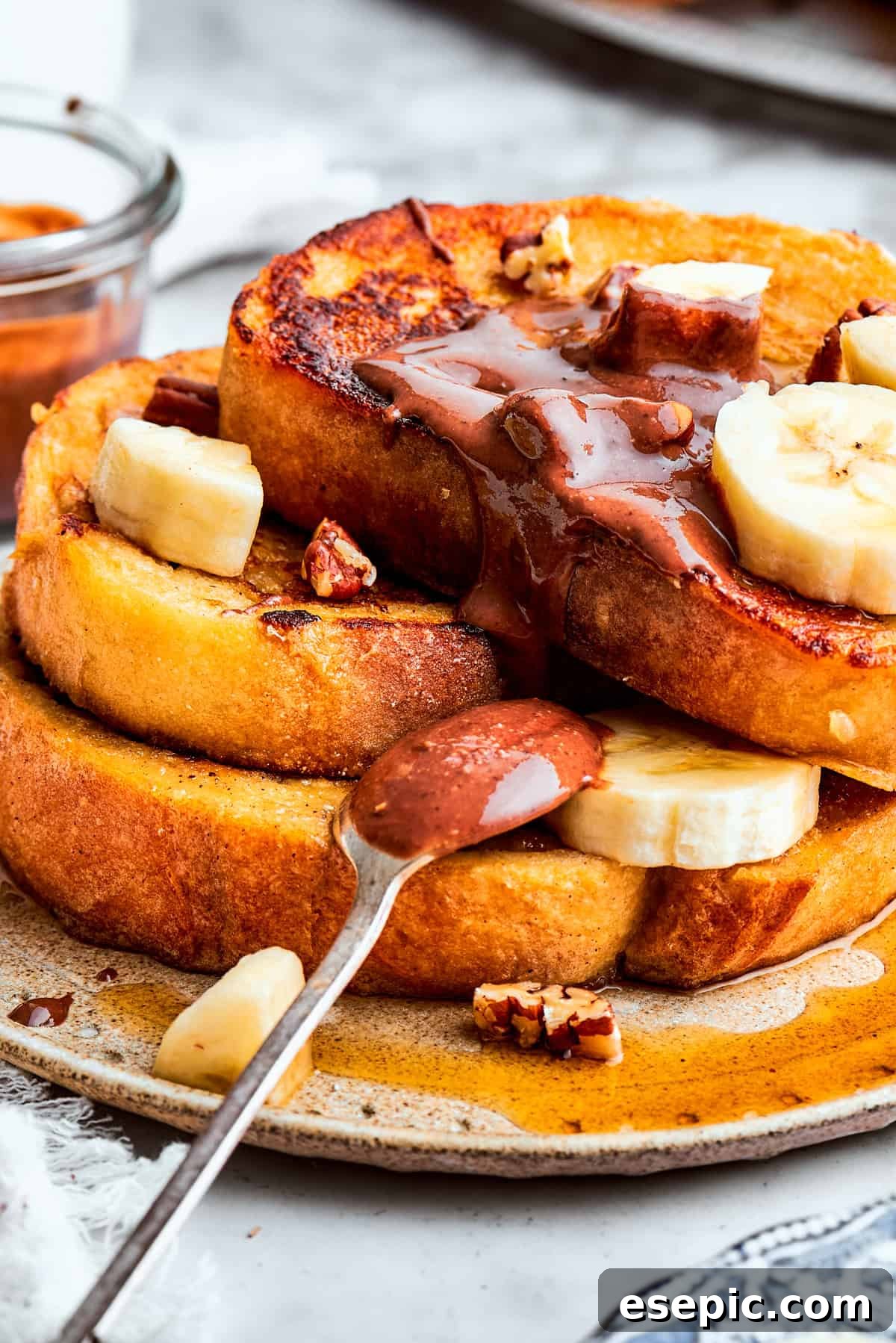 Close-up of a stack of French toast garnished with slices of banana and chocolate spread.