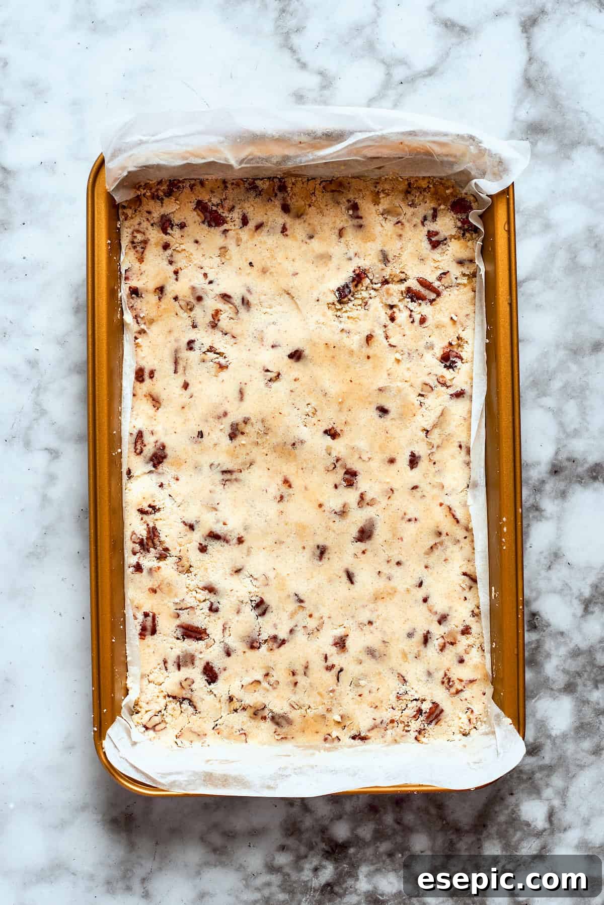 The pecan crust mixture is firmly pressed into the bottom of a 9x13-inch baking pan.