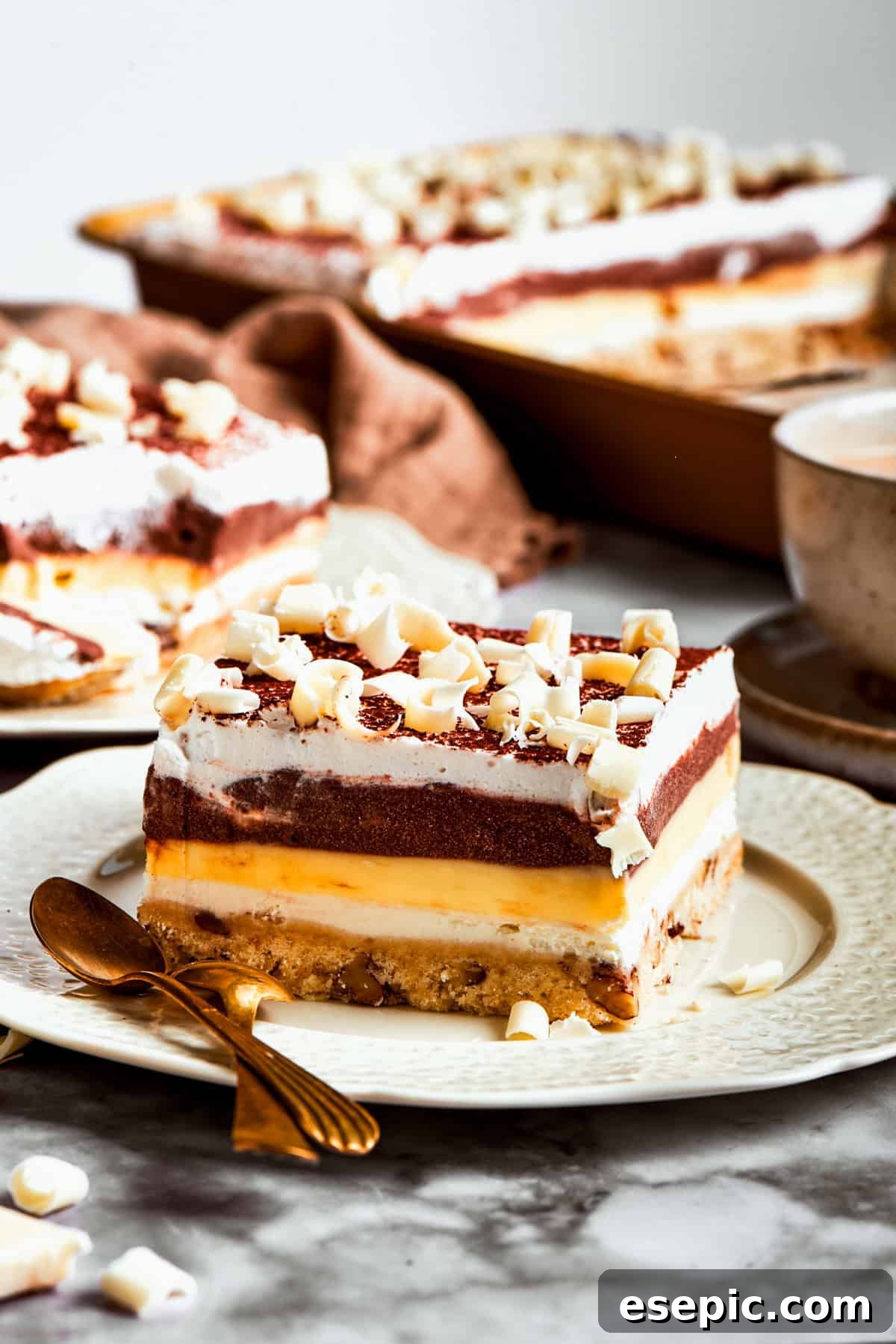 A perfectly sliced square of Sex in a Pan dessert, garnished with cocoa and white chocolate, ready to be served and enjoyed.