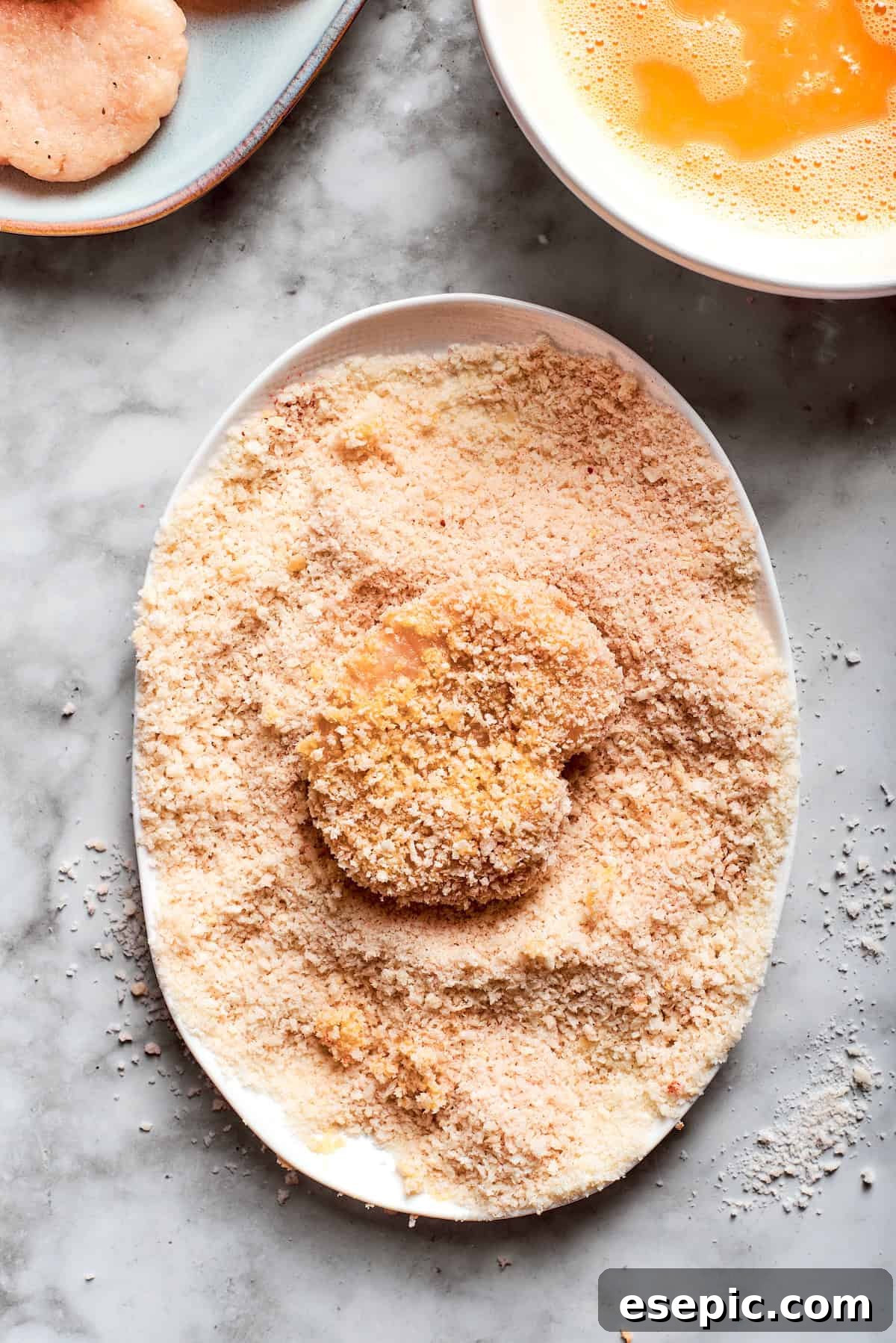 This easy homemade Chicken Nuggets Recipe features perfectly cooked homemade chicken nuggets that are crispy outside and juicy on the inside. A nugget is dipped in bread crumbs.