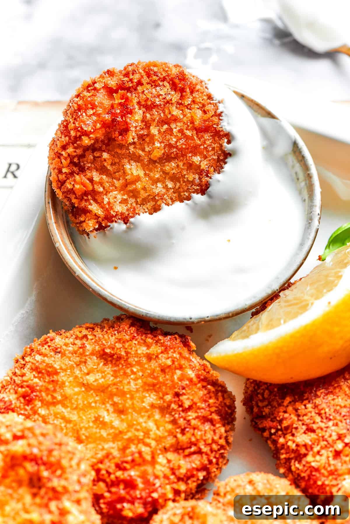 This easy homemade Chicken Nuggets Recipe features perfectly cooked homemade chicken nuggets that are crispy outside and juicy on the inside. A chicken nugget in a dish of Ranch dip.