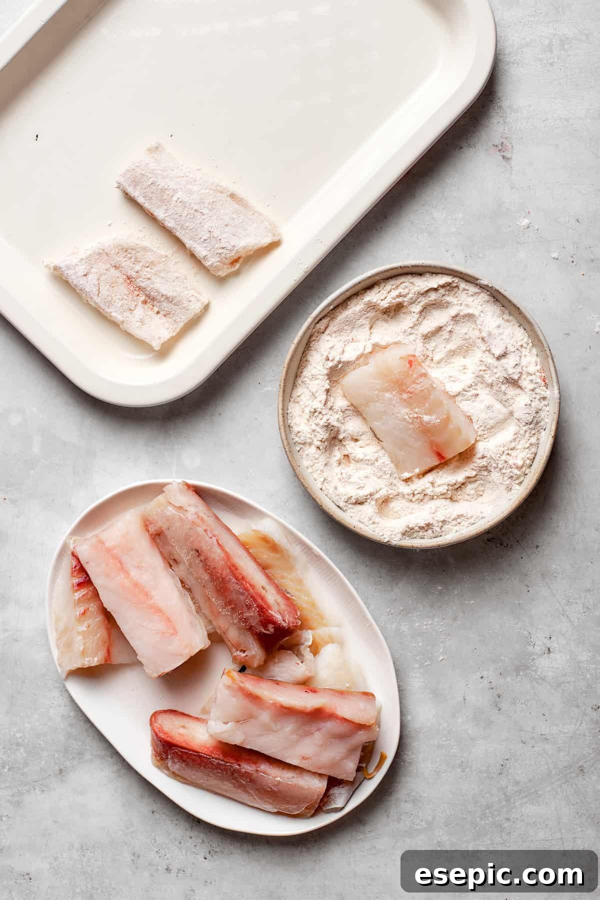 A piece of fresh fish being generously dredged in a seasoned flour mixture, ensuring it's fully coated before dipping into the beer batter.