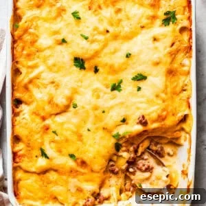 Overhead image of hamburger potato casserole in a baking dish, with a serving of it missing from the corner.