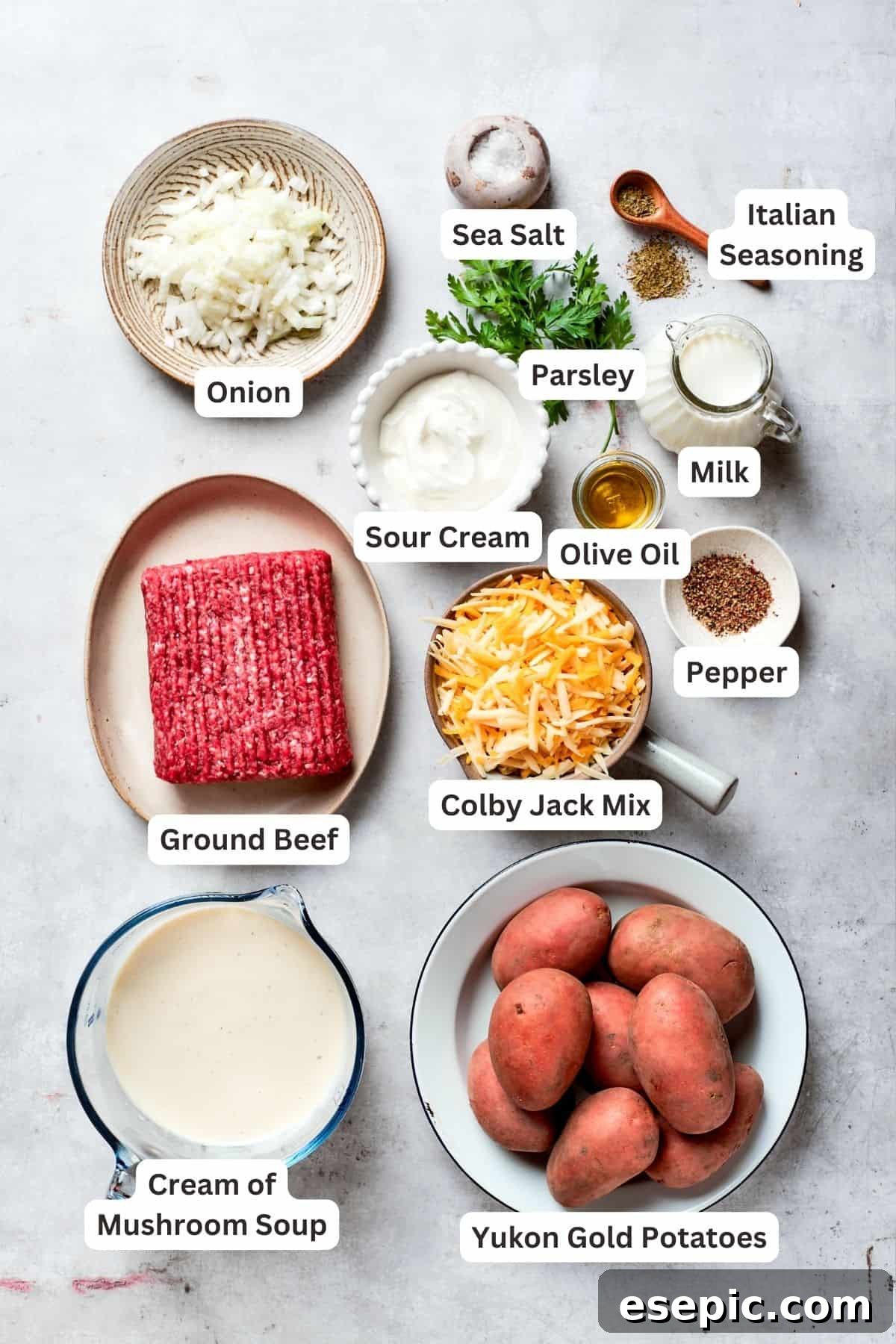 Ingredients for hamburger potato casserole: ground beef, cheese mix, onion, sour cream, salt, pepper, milk, seasoning, mushroom soup, potatoes.