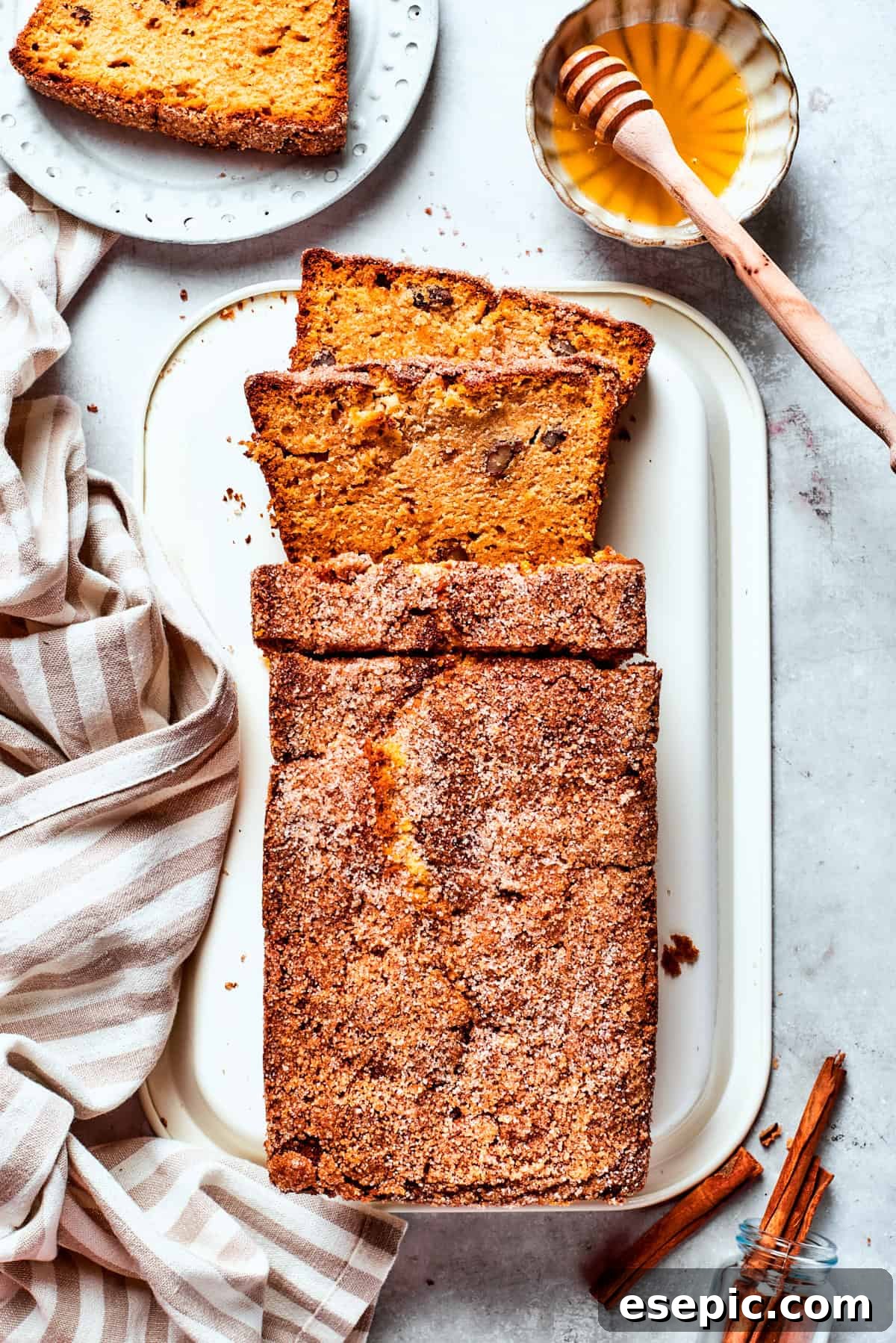 A serving platter with a loaf of Amish friendship bread with a slice cut out next to a bowl of honey.