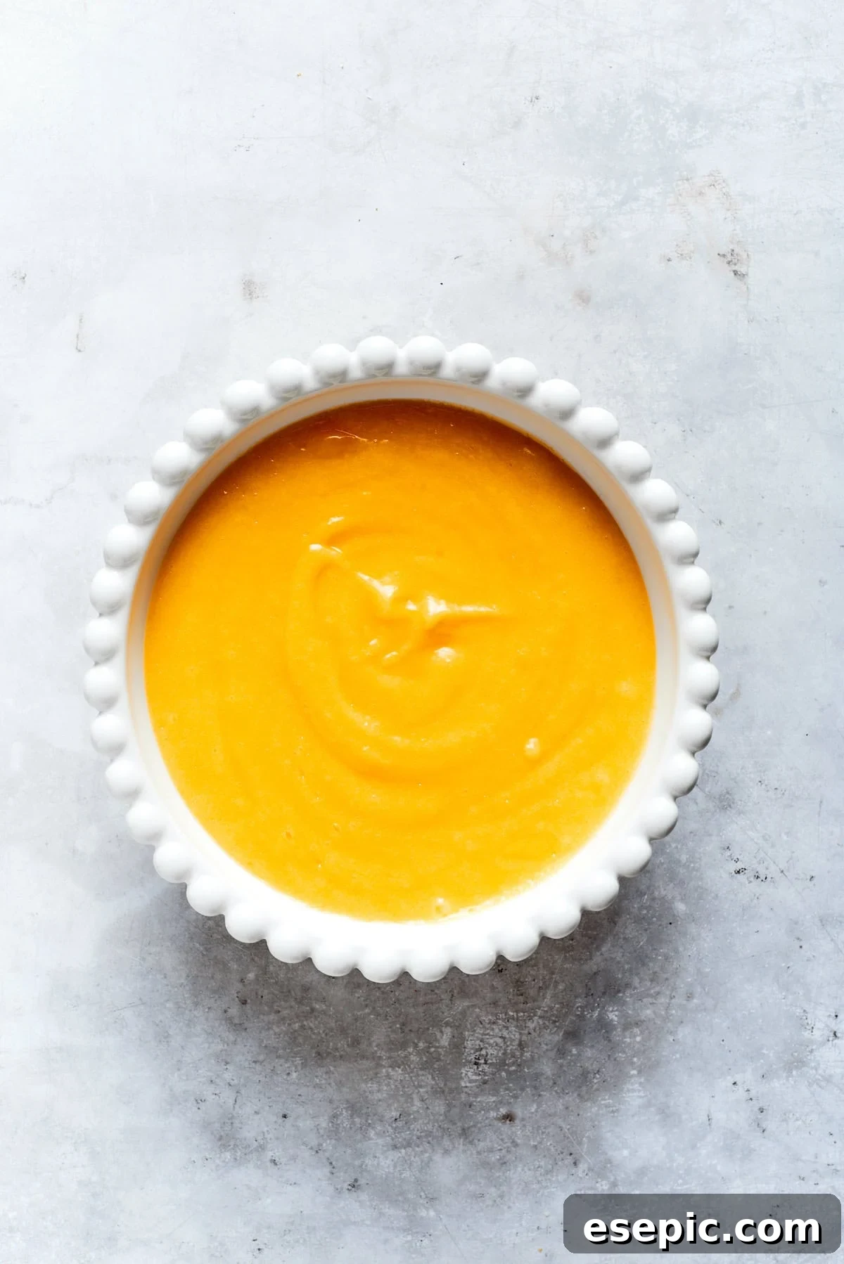 Smooth, vibrant yellow lemon curd resting in a clear glass bowl, ready to be used.