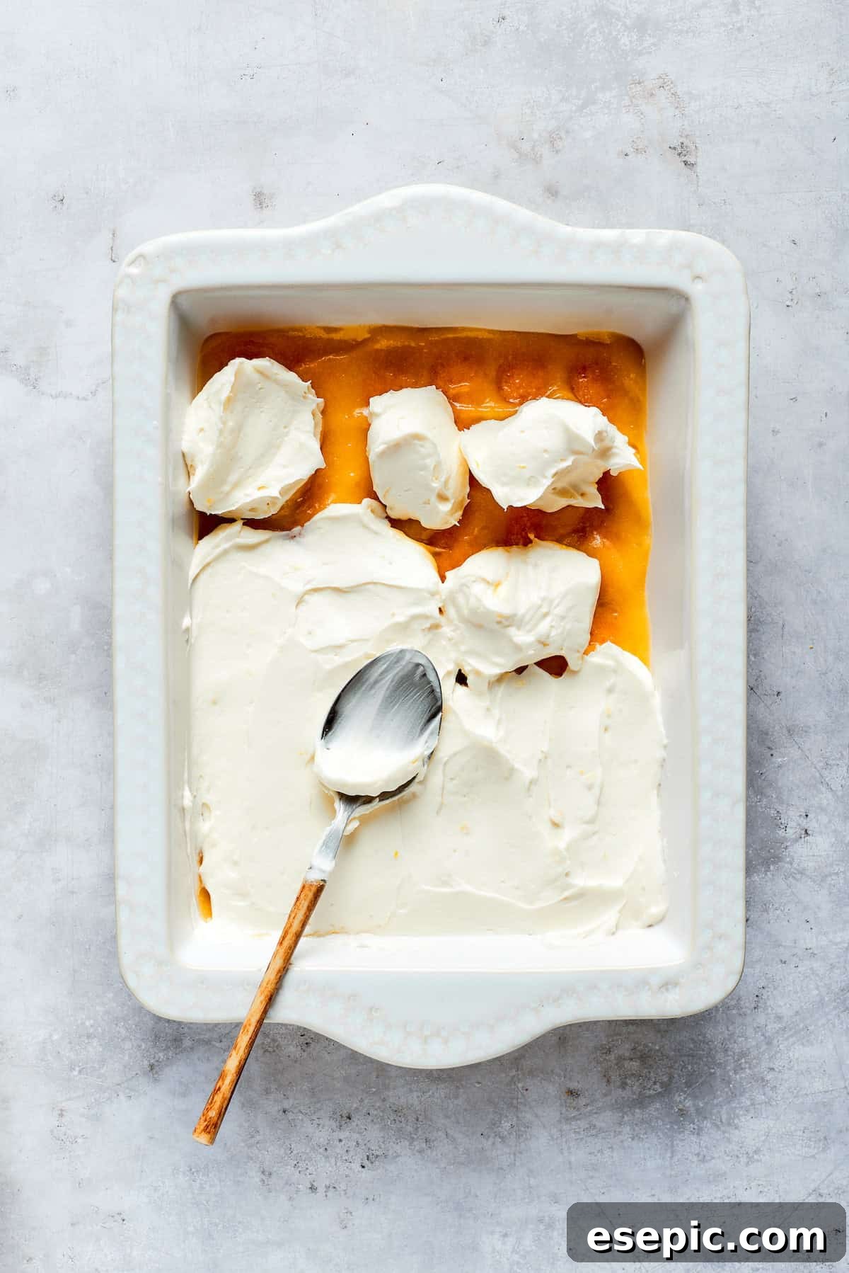 A thick, smooth layer of mascarpone cream filling is carefully spread over the lemon curd and ladyfingers.