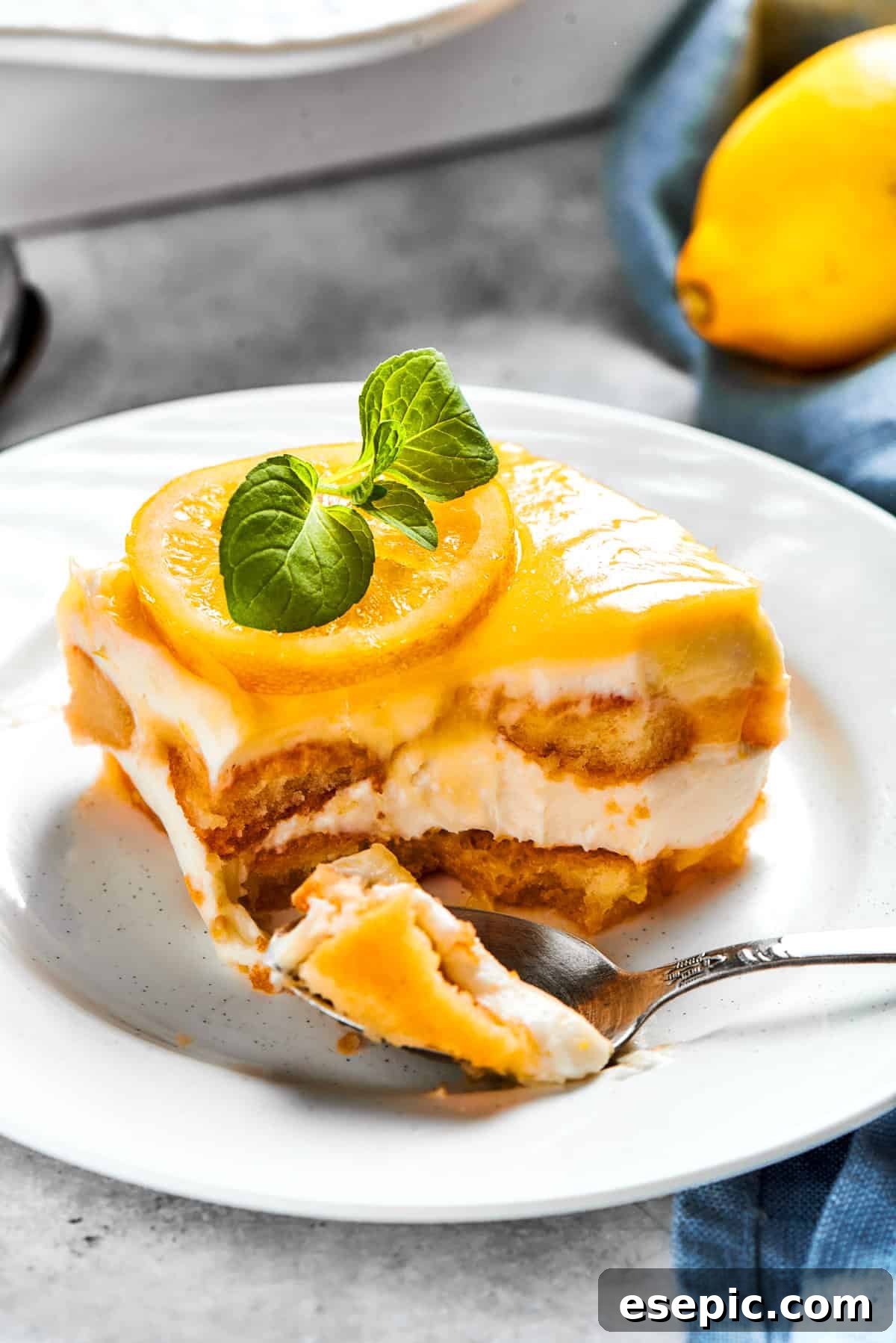 A fork cutting into a portion of lemon tiramisu served on a small dessert plate, showing its inviting texture.