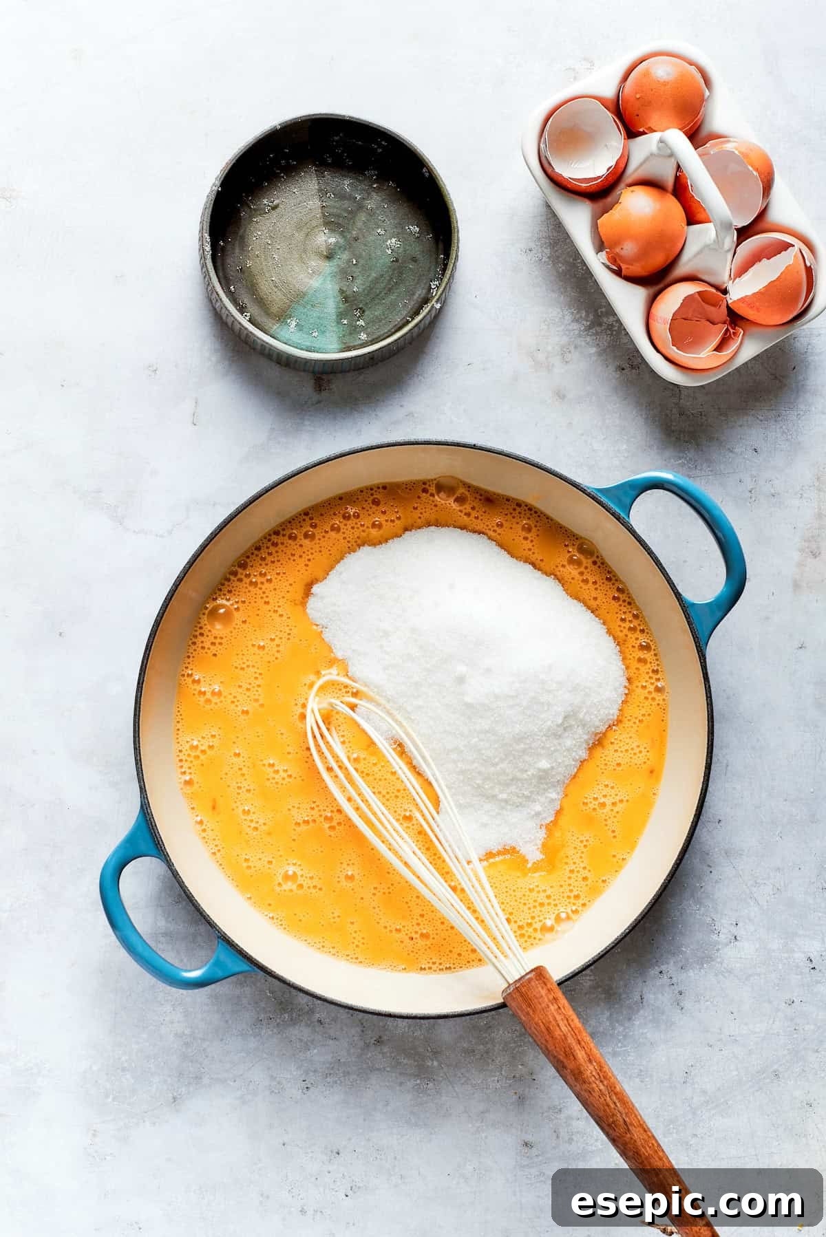 Granulated sugar is vigorously whisked into lemon juice and eggs in a heatproof bowl over heat.
