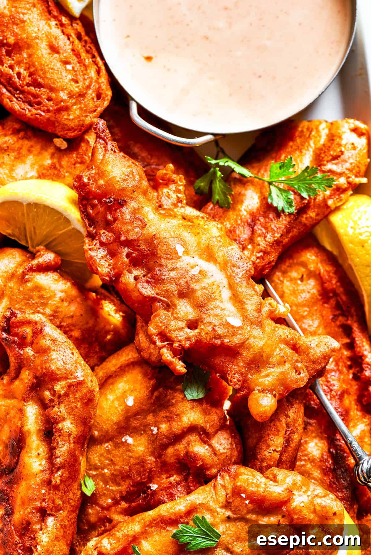 Closeup photo of battered chicken arranged on a plate with a bowl of dipping sauce.