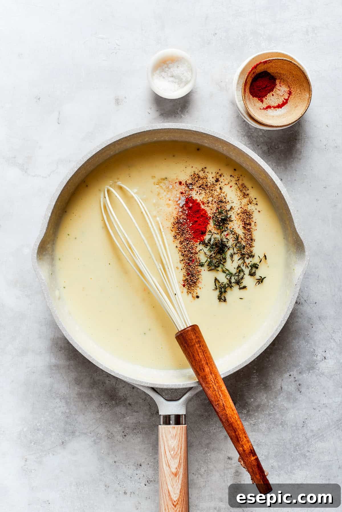 Seasonings including salt, pepper, thyme, and paprika are sprinkled into the simmering sauce, enhancing its flavor profile.