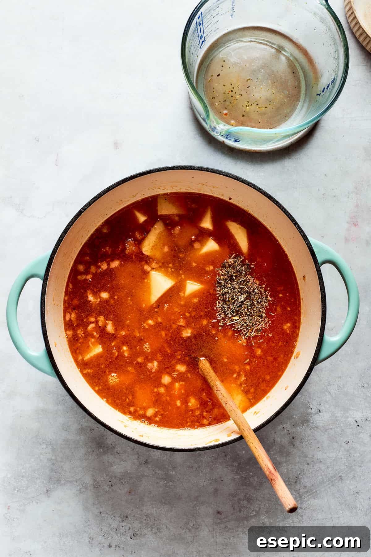 Chicken broth is poured into the pot with the soup ingredients, ready for simmering.