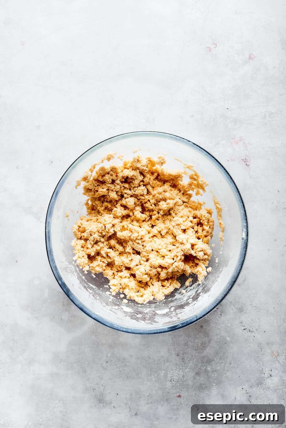 Millionaire Bars are decadent layers of homemade buttery shortbread, creamy caramel, and thick chocolate ganache. Close-up of the prepared shortbread dough in a mixing bowl, ready to be pressed into a pan.