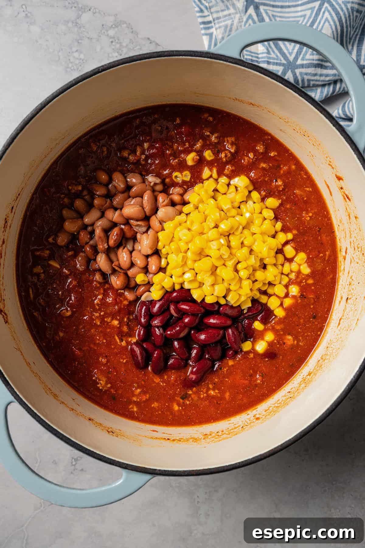 Canned corn and beans added to a pot with turkey chili.