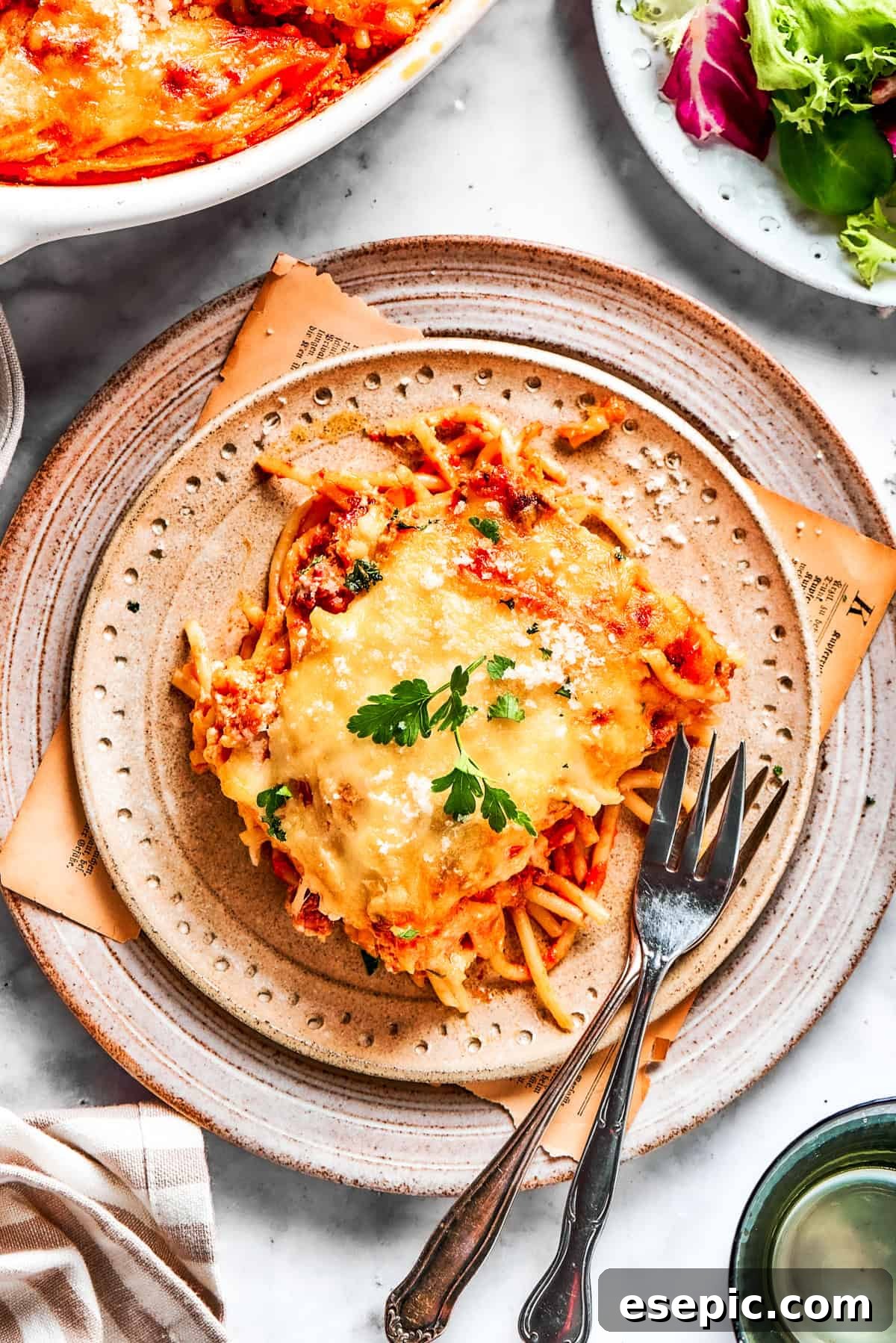 A delicious serving of million dollar spaghetti on a white plate, garnished with fresh herbs, ready to be enjoyed.