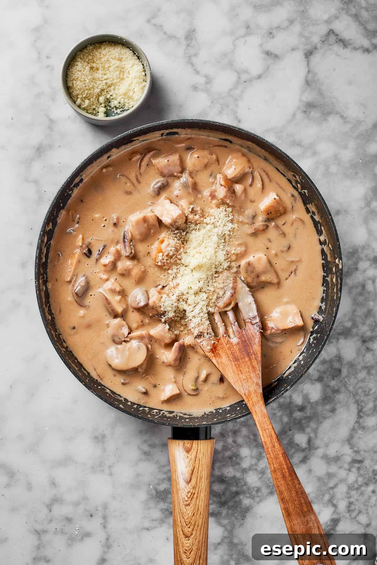 Cooked chicken pieces, chicken broth, heavy cream, sour cream, and Parmesan cheese added to the rich Marsala sauce in a skillet.