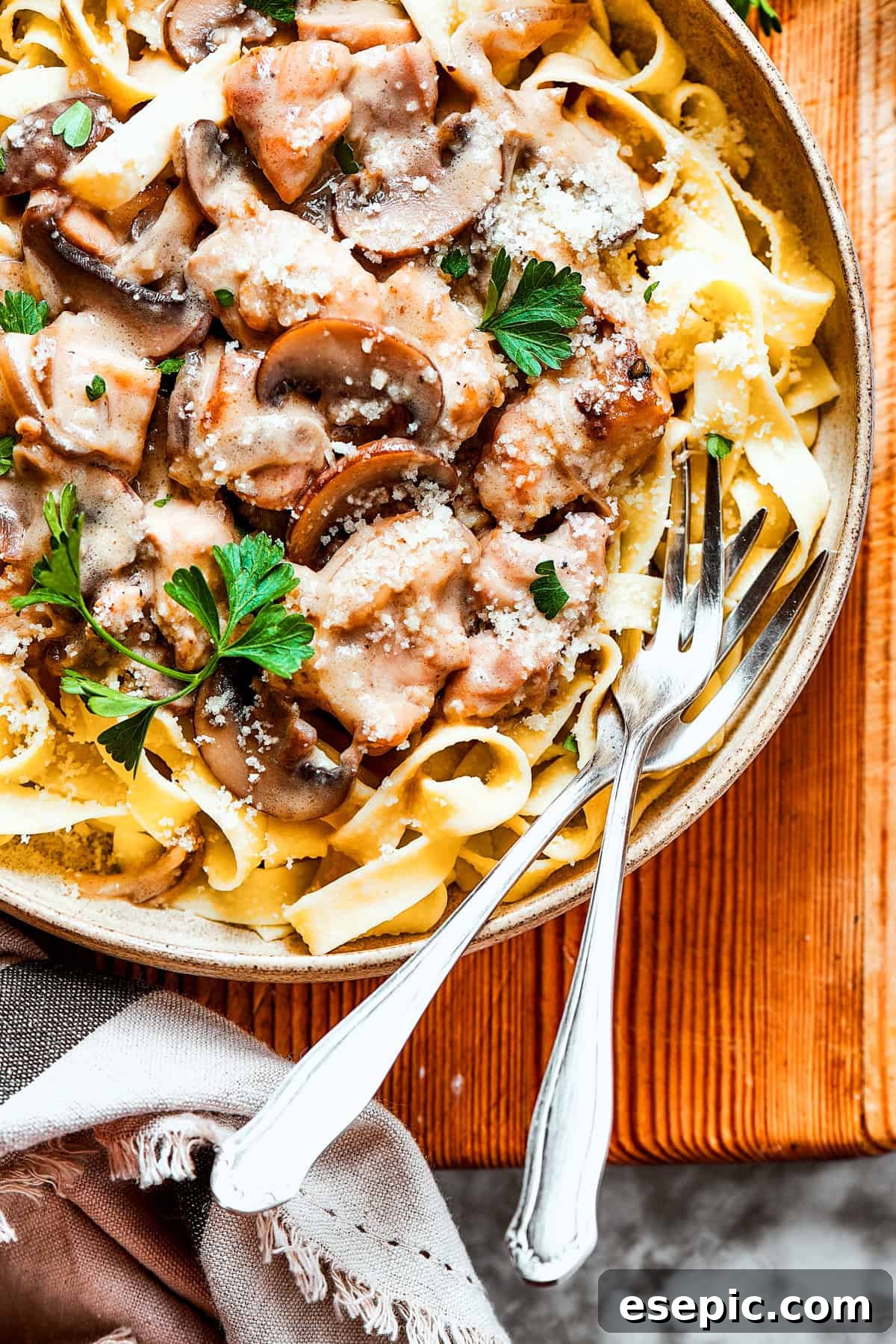 A large bowl of creamy chicken Marsala fettuccine with two forks resting inside, ready to be enjoyed.