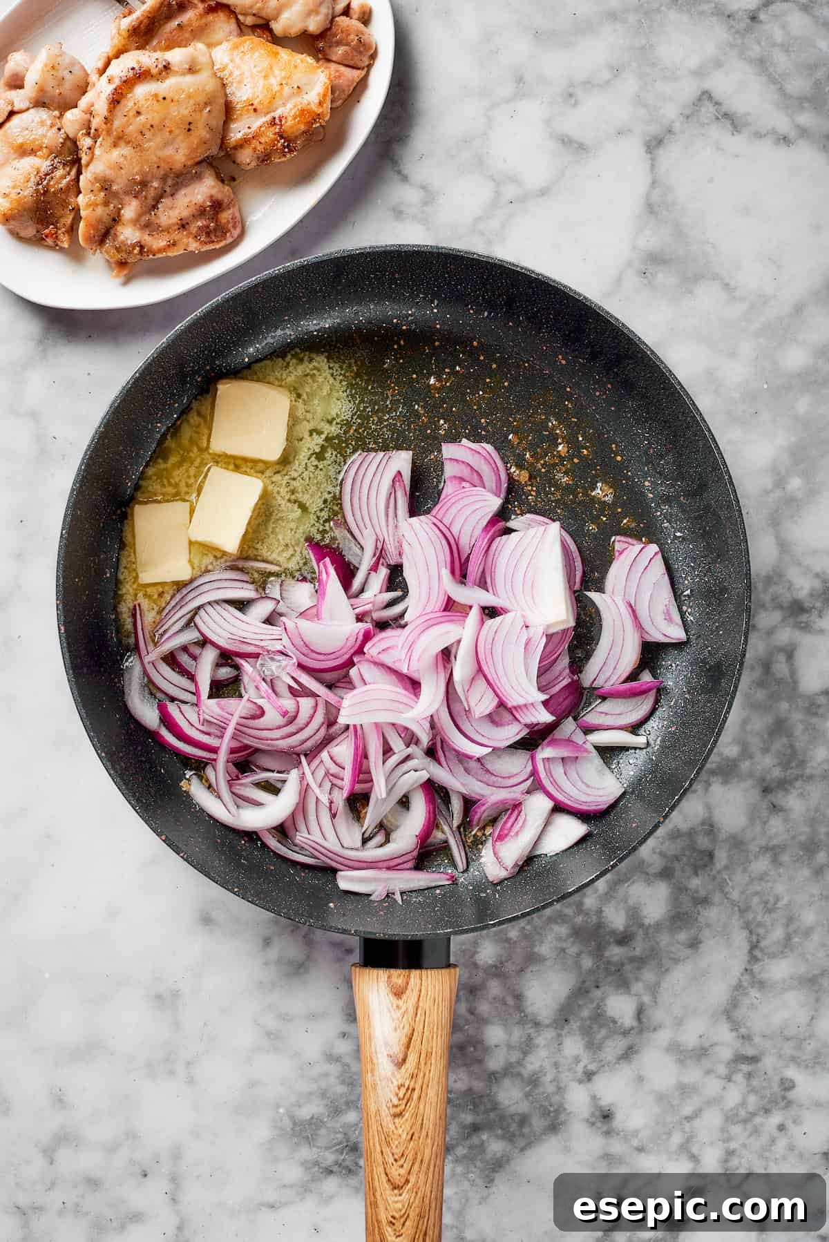 Thinly sliced red onions caramelizing in melted butter in a pan.