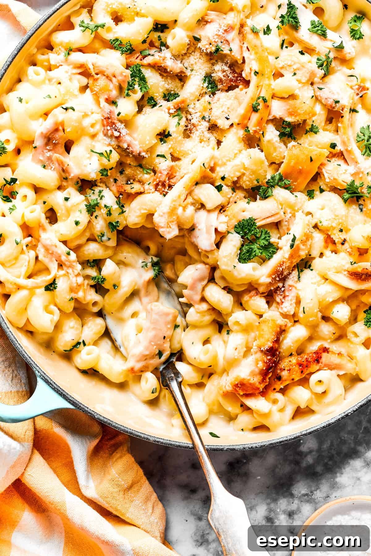 Creamy Garlic Parmesan Chicken Pasta 2 Close-up image of creamy garlic parmesan chicken pasta in a skillet, with a serving spoon resting inside.
