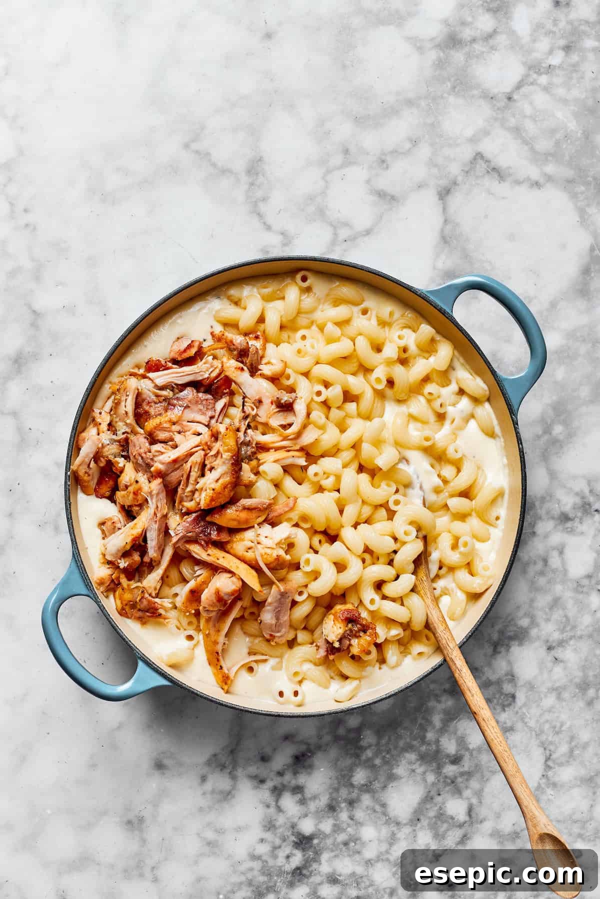 Creamy Garlic Parmesan Chicken Pasta 12 Cooked pasta noodles and shredded chicken being added to the creamy sauce in a large pan, ready to be tossed together.