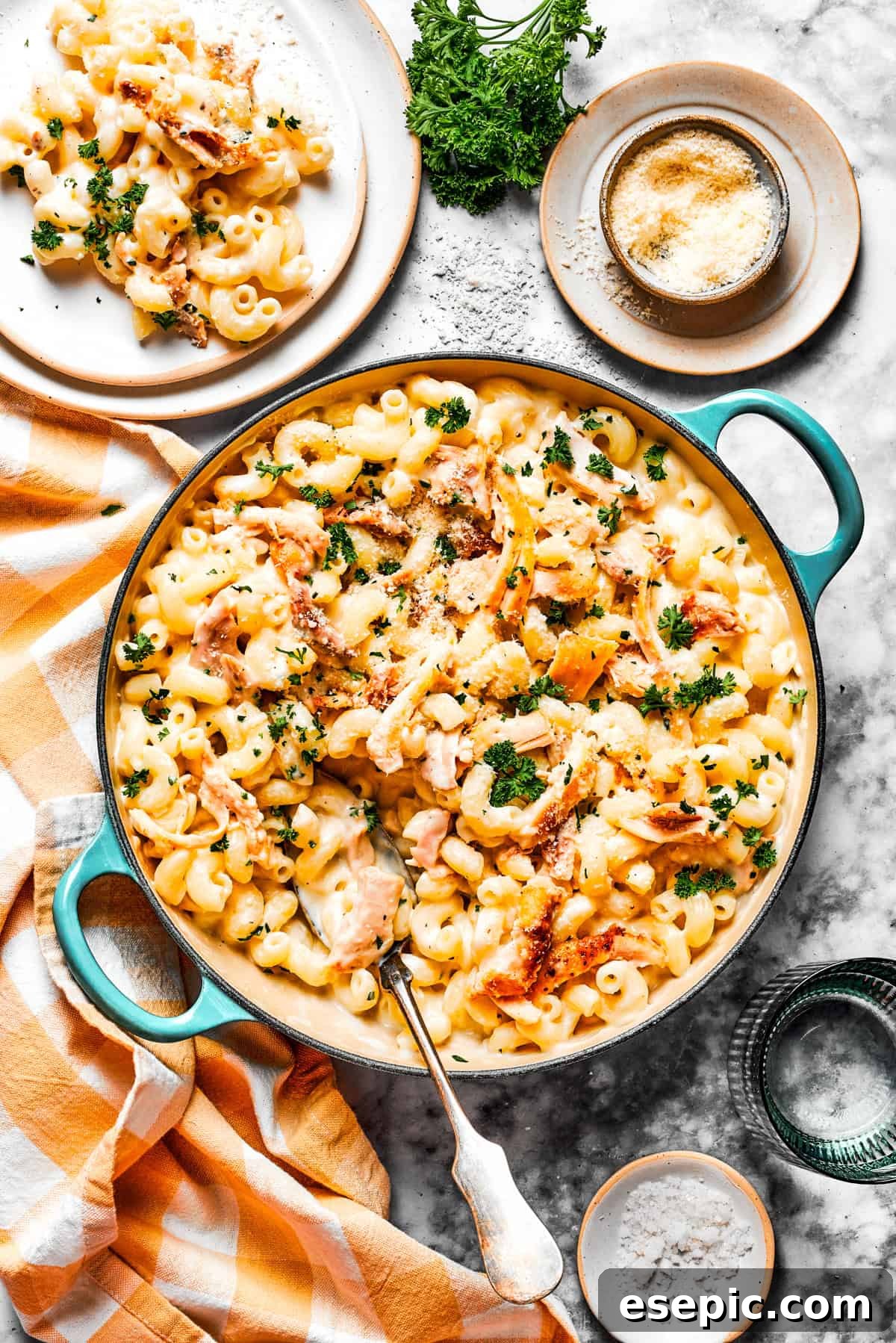 Creamy Garlic Parmesan Chicken Pasta 13 An inviting overhead view of creamy garlic parmesan chicken pasta in a large pot, with a separate serving on a dinner plate beside it.