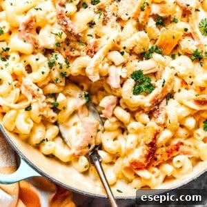 Close-up image of creamy garlic parmesan chicken pasta in a skillet, with a serving spoon resting inside.