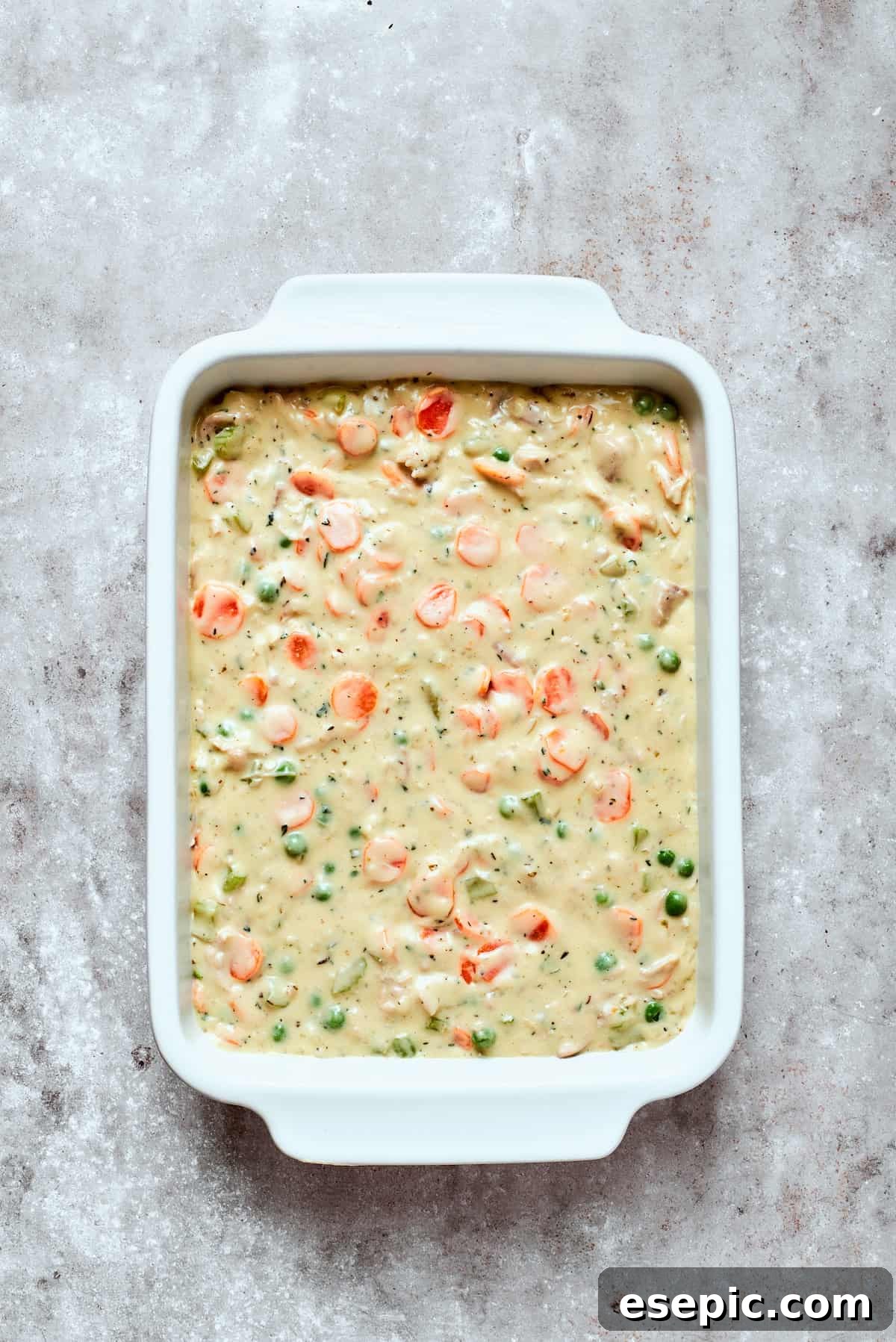 Cozy Chicken Pot Pie Casserole Recipe The completed chicken pot pie filling spooned into a prepared baking dish, ready for the biscuit topping.