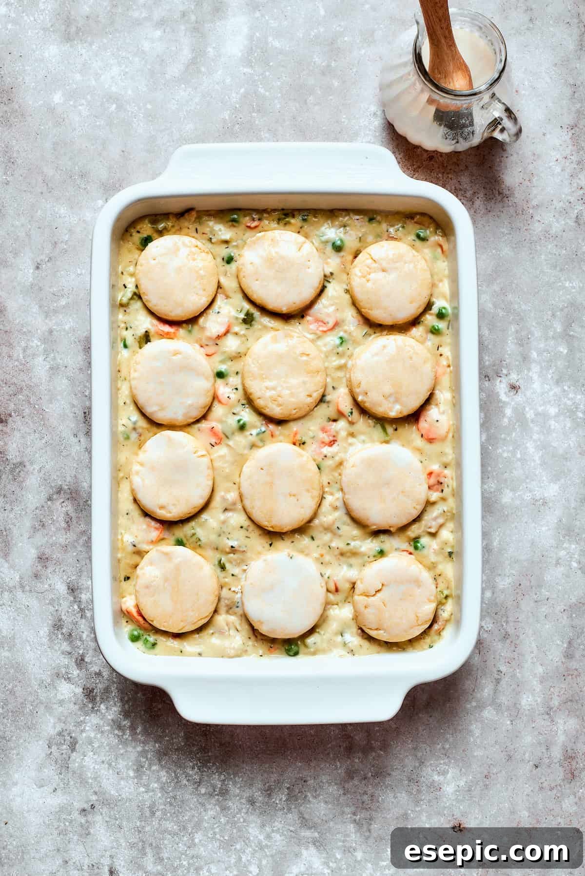 Cozy Chicken Pot Pie Casserole Recipe A chicken pot pie casserole assembled with biscuit topping arranged neatly in rows, ready for baking.
