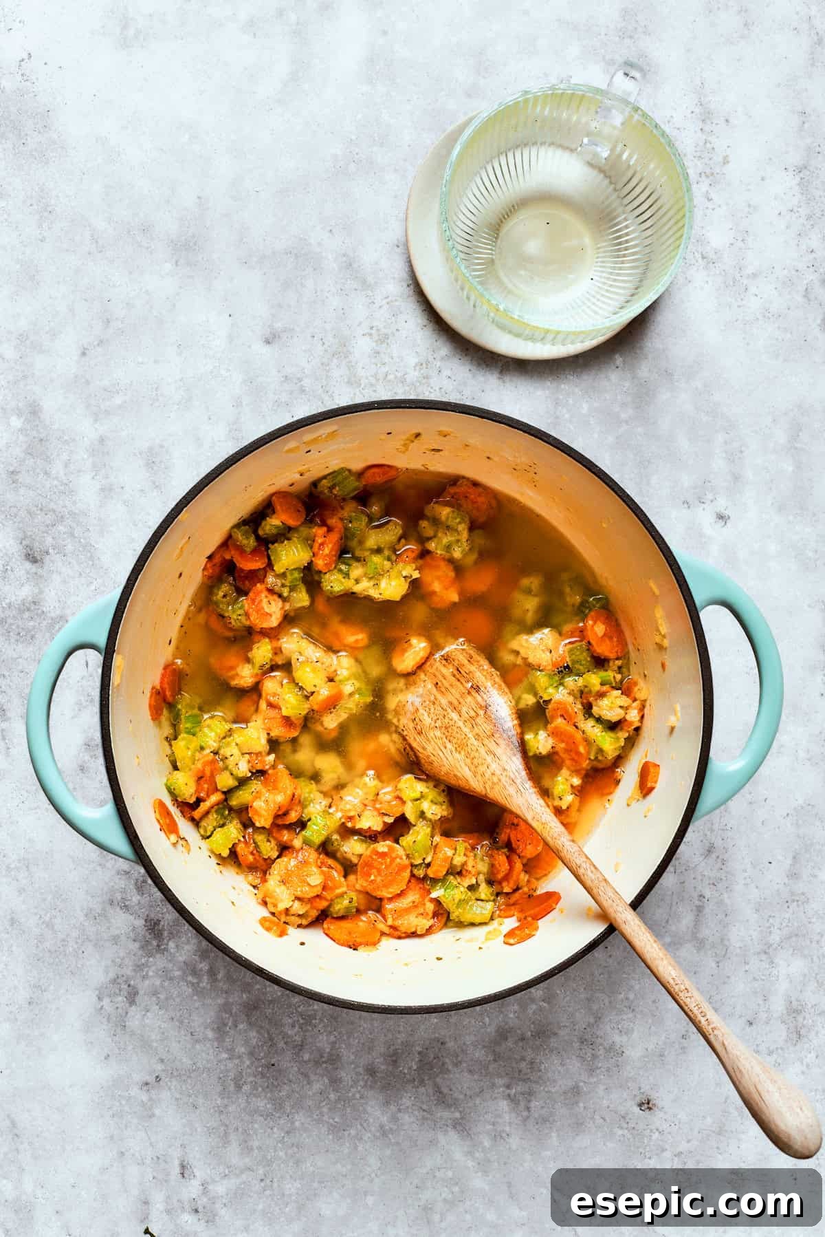 Chicken pot pie casserole is everything you love about the classic comfort food, baked under fluffy buttermilk biscuits instead of pie crust! Pouring chicken broth into a pot of sautéed vegetables, creating the base for the pot pie filling.
