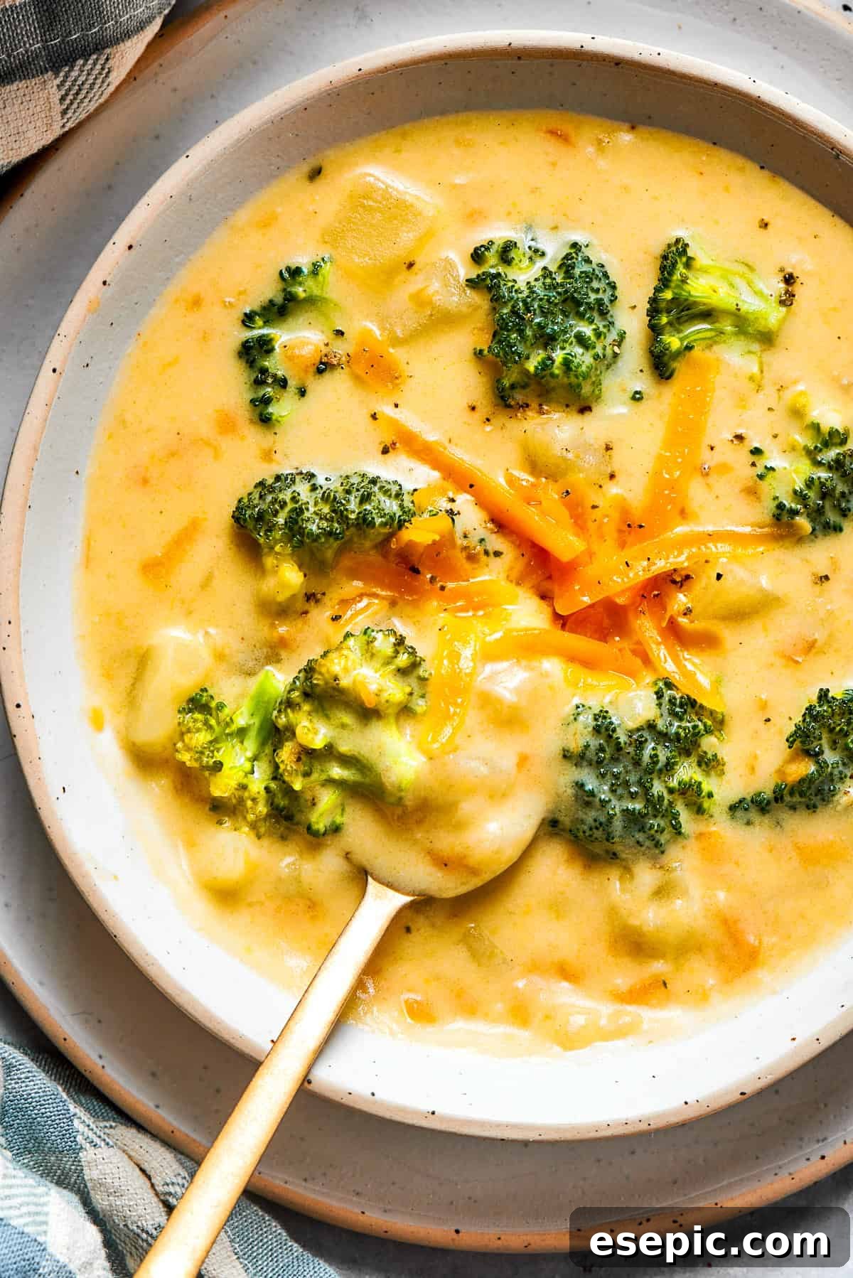 This easy broccoli cheddar soup recipe is packed with cozy flavor, featuring broccoli florets, diced potatoes, and freshly grated cheddar cheese. A steaming bowl of homemade broccoli cheese soup, garnished with shredded cheddar and fresh broccoli florets.