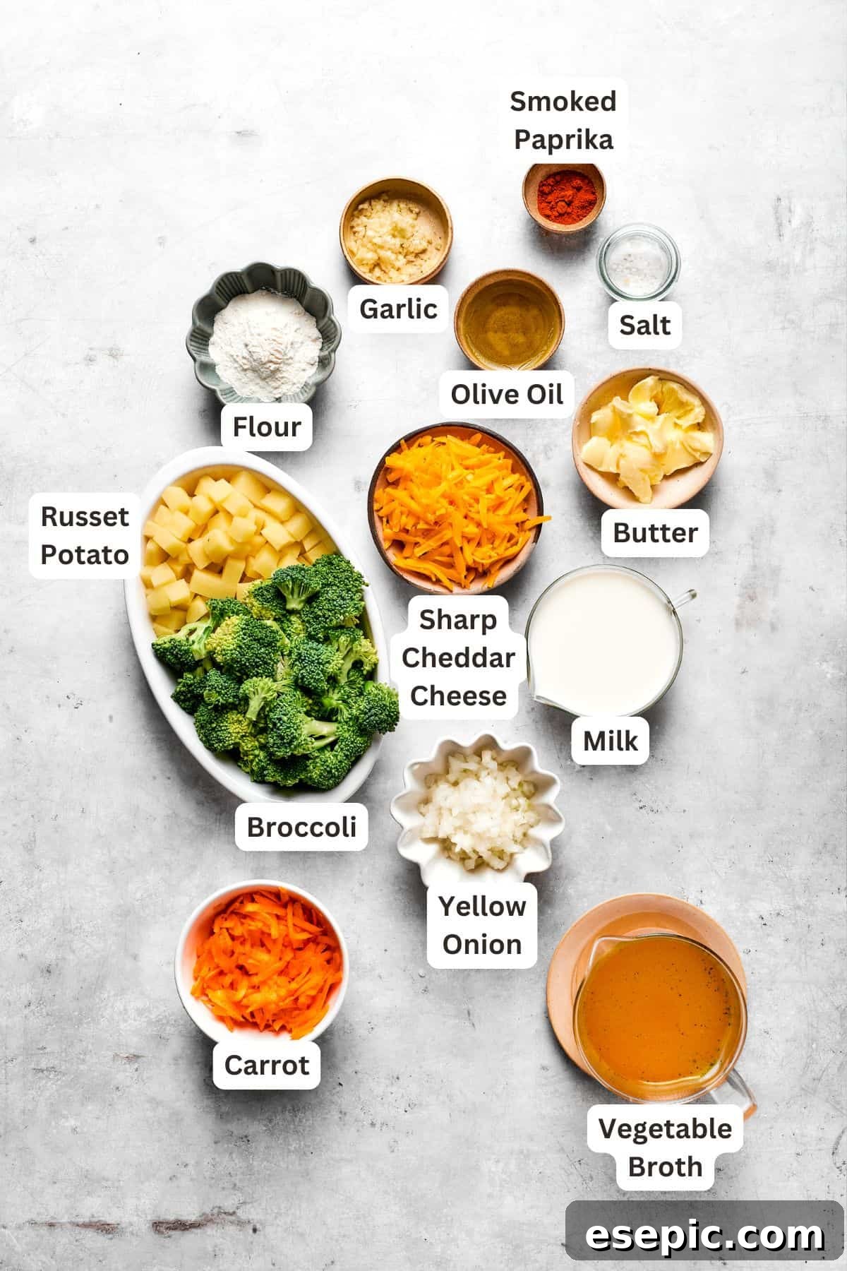 This easy broccoli cheddar soup recipe is packed with cozy flavor, featuring broccoli florets, diced potatoes, and freshly grated cheddar cheese. A selection of fresh ingredients laid out for making broccoli cheese soup, including broccoli, carrots, onions, potatoes, cheese, and milk.