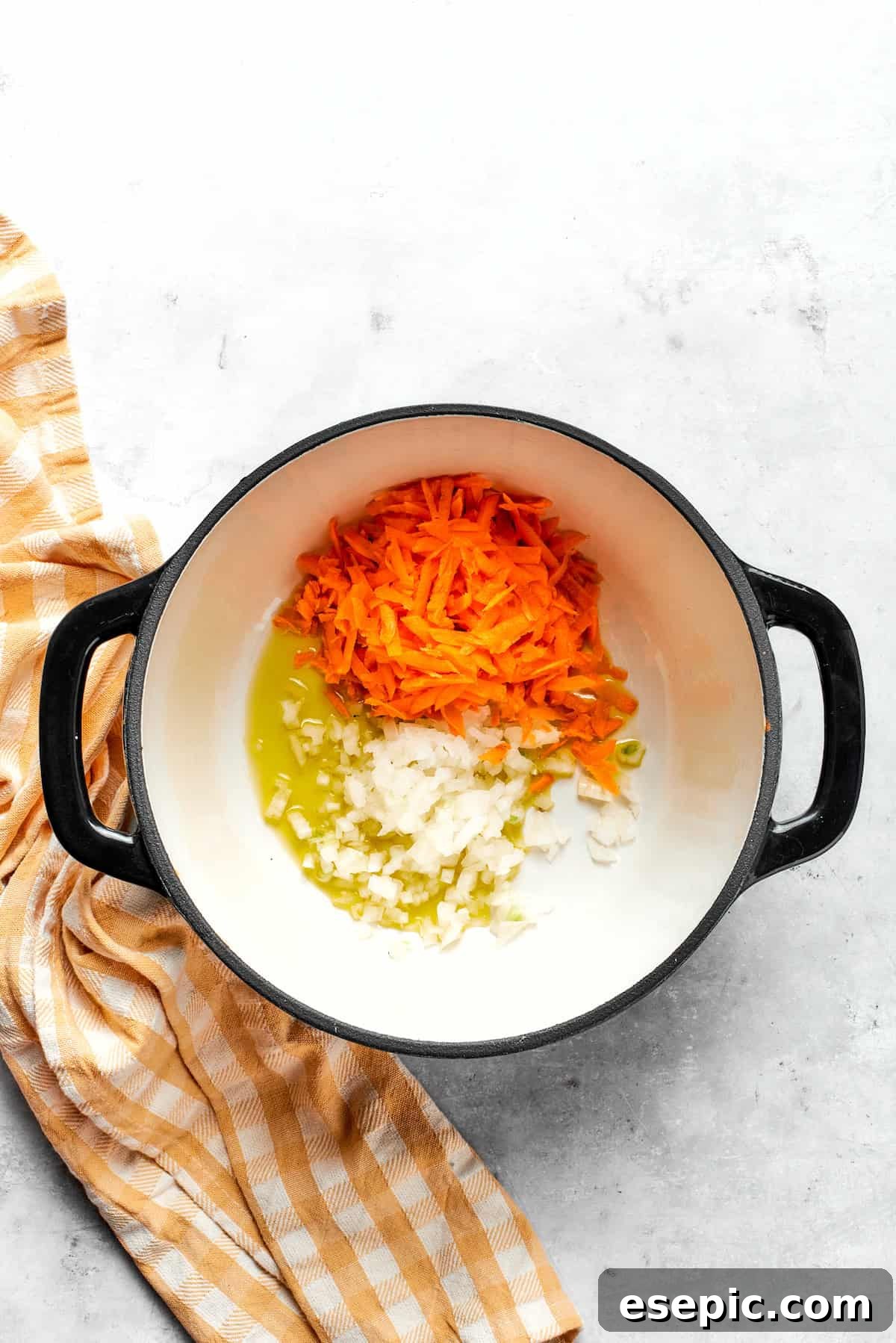 This easy broccoli cheddar soup recipe is packed with cozy flavor, featuring broccoli florets, diced potatoes, and freshly grated cheddar cheese. Cooking carrots and onion in a pot.