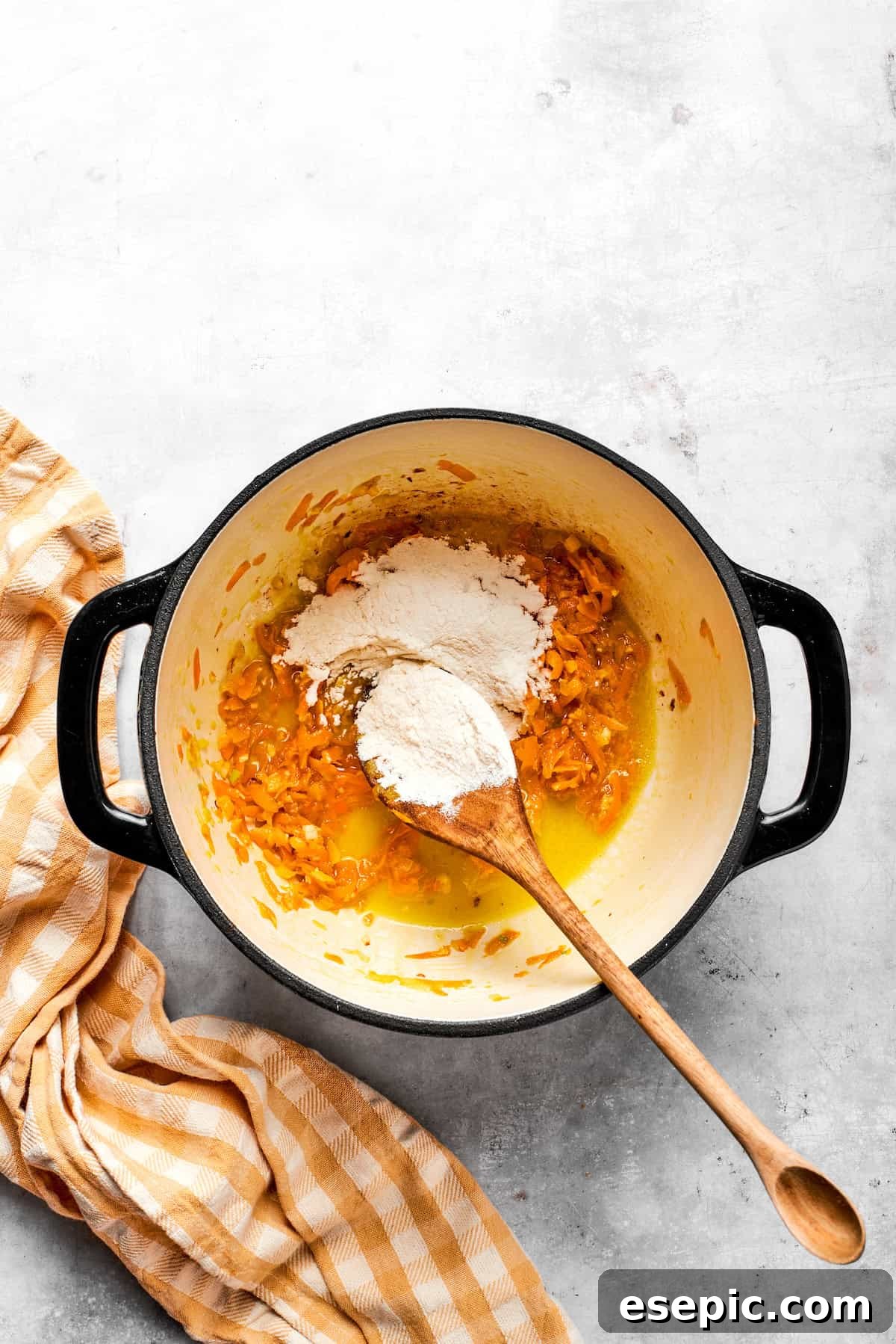 This easy broccoli cheddar soup recipe is packed with cozy flavor, featuring broccoli florets, diced potatoes, and freshly grated cheddar cheese. Adding flour to a pot with carrots and butter.