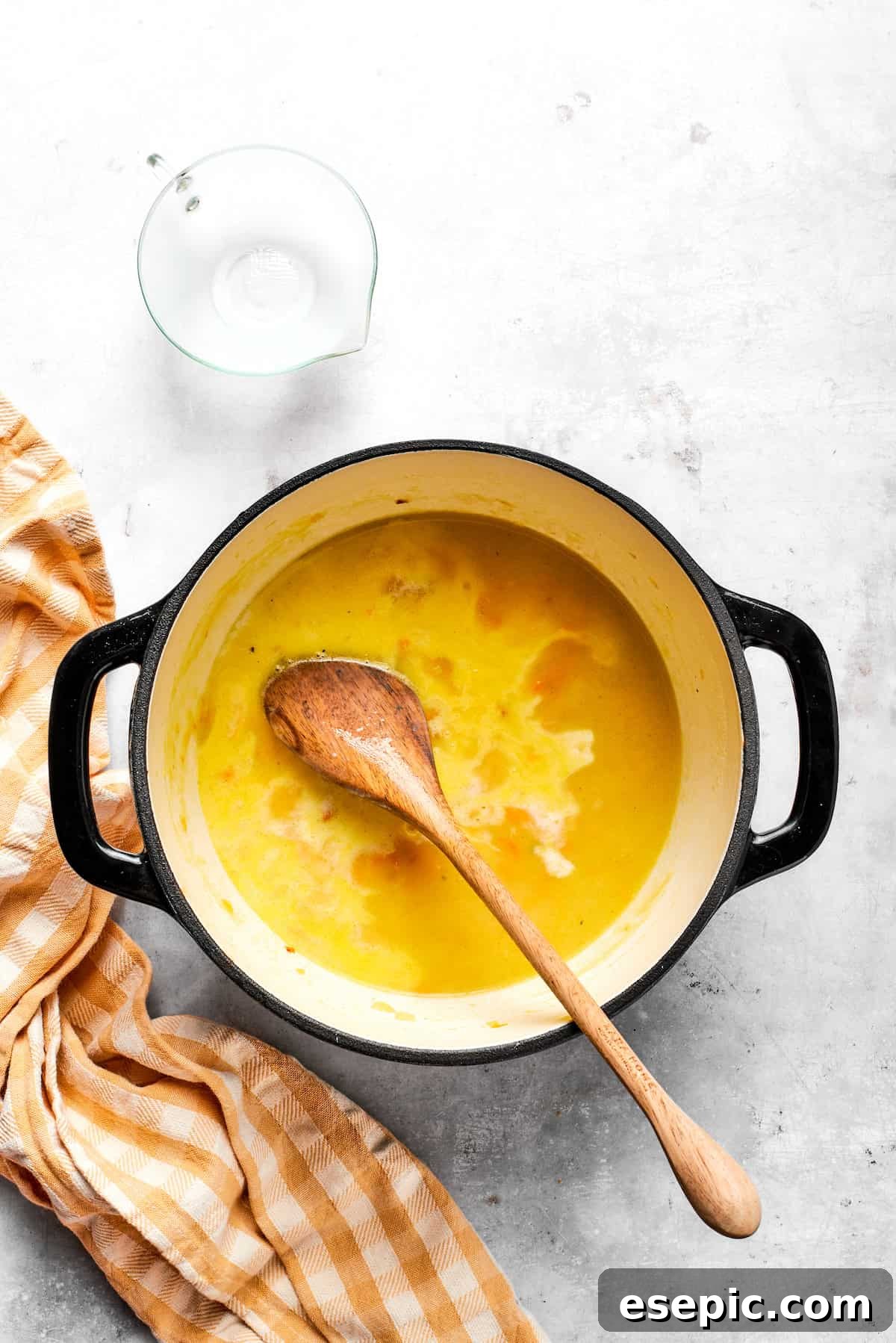 This easy broccoli cheddar soup recipe is packed with cozy flavor, featuring broccoli florets, diced potatoes, and freshly grated cheddar cheese. Adding milk to the pot.