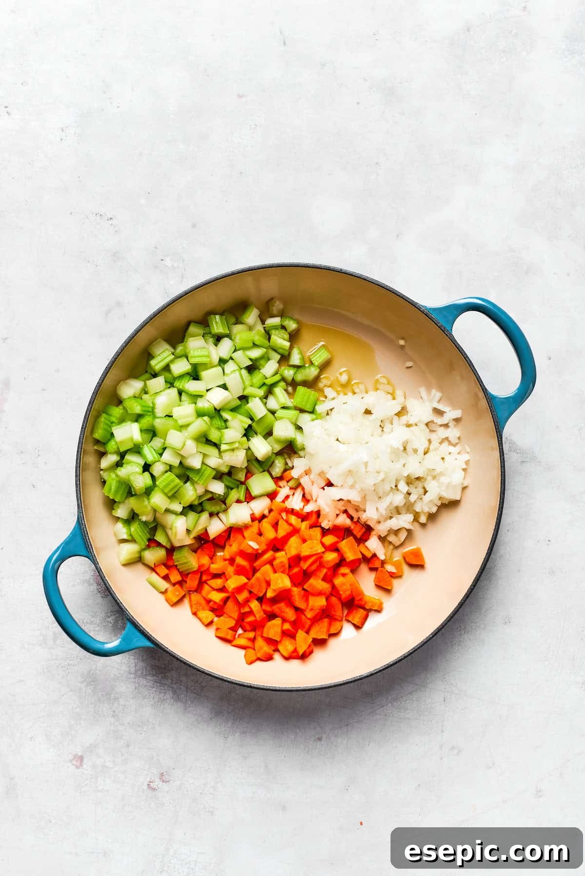 Sautéing diced onions, carrots, and celery in a pot.