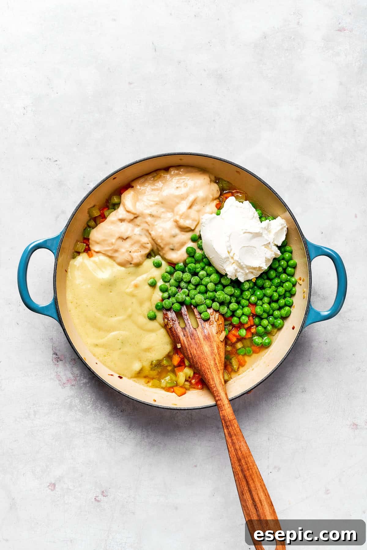 Adding sour cream, condensed soups, and peas to the sautéed vegetables.