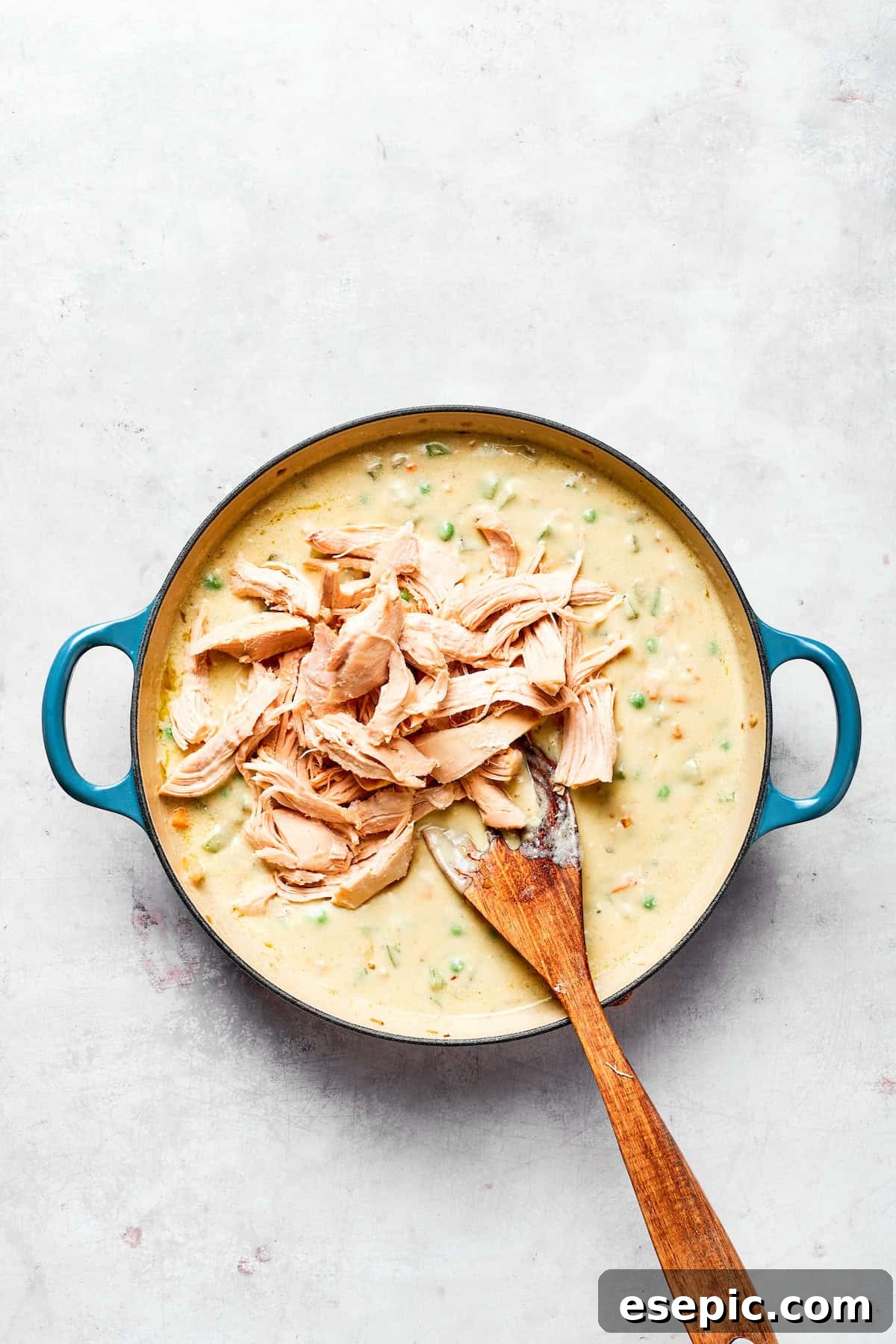 Mixing in the shredded chicken with the creamy vegetable filling.