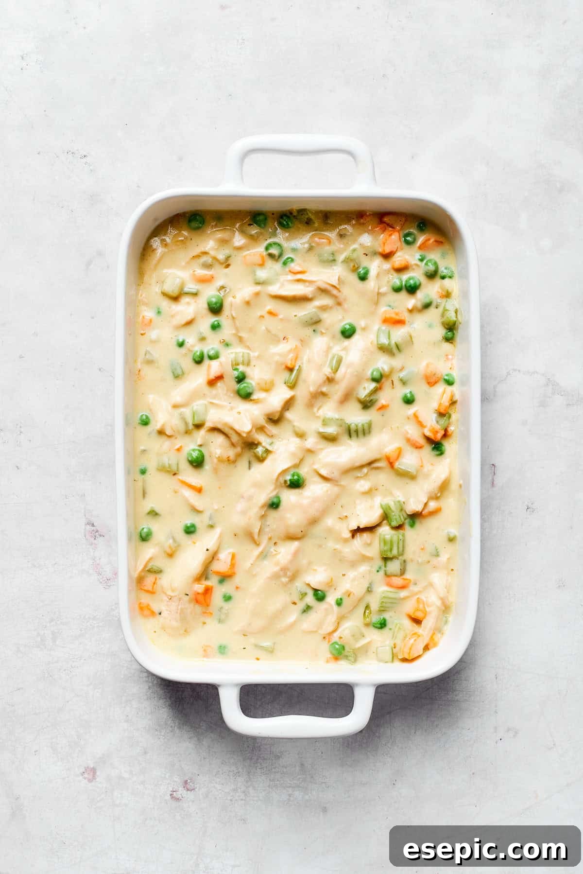 Creamy chicken filling spread evenly in a 9x13 baking dish.