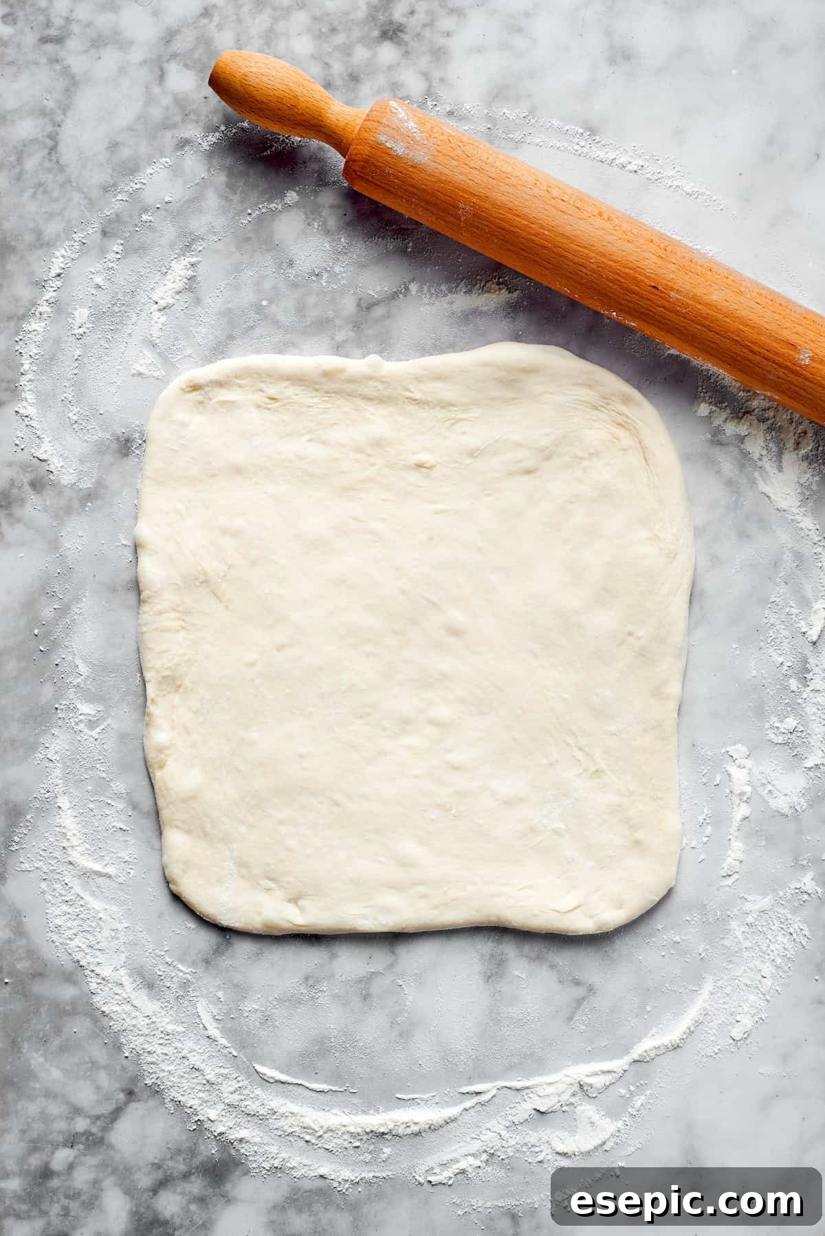 Pizza dough rolled into a square.