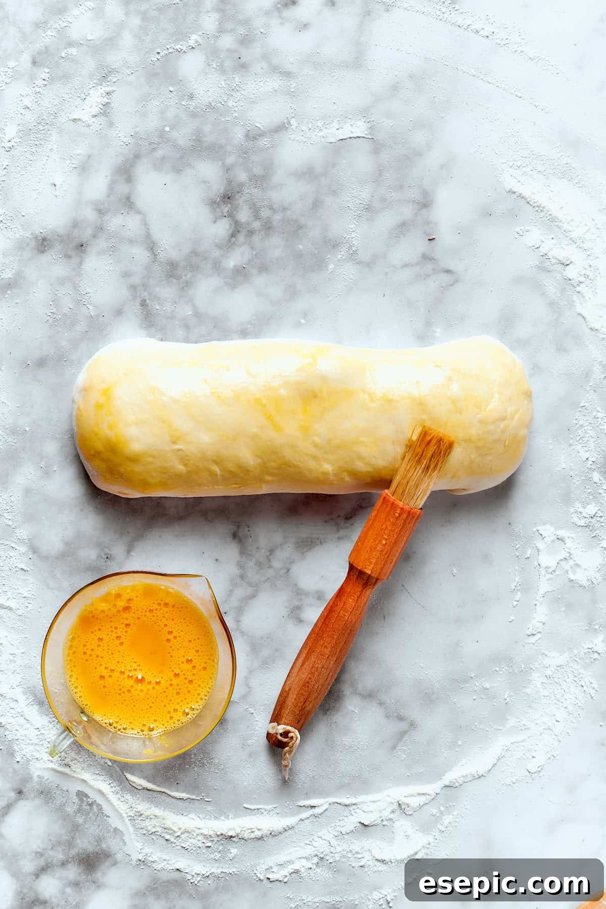 A roll of Costco chicken bake is brushed with egg.