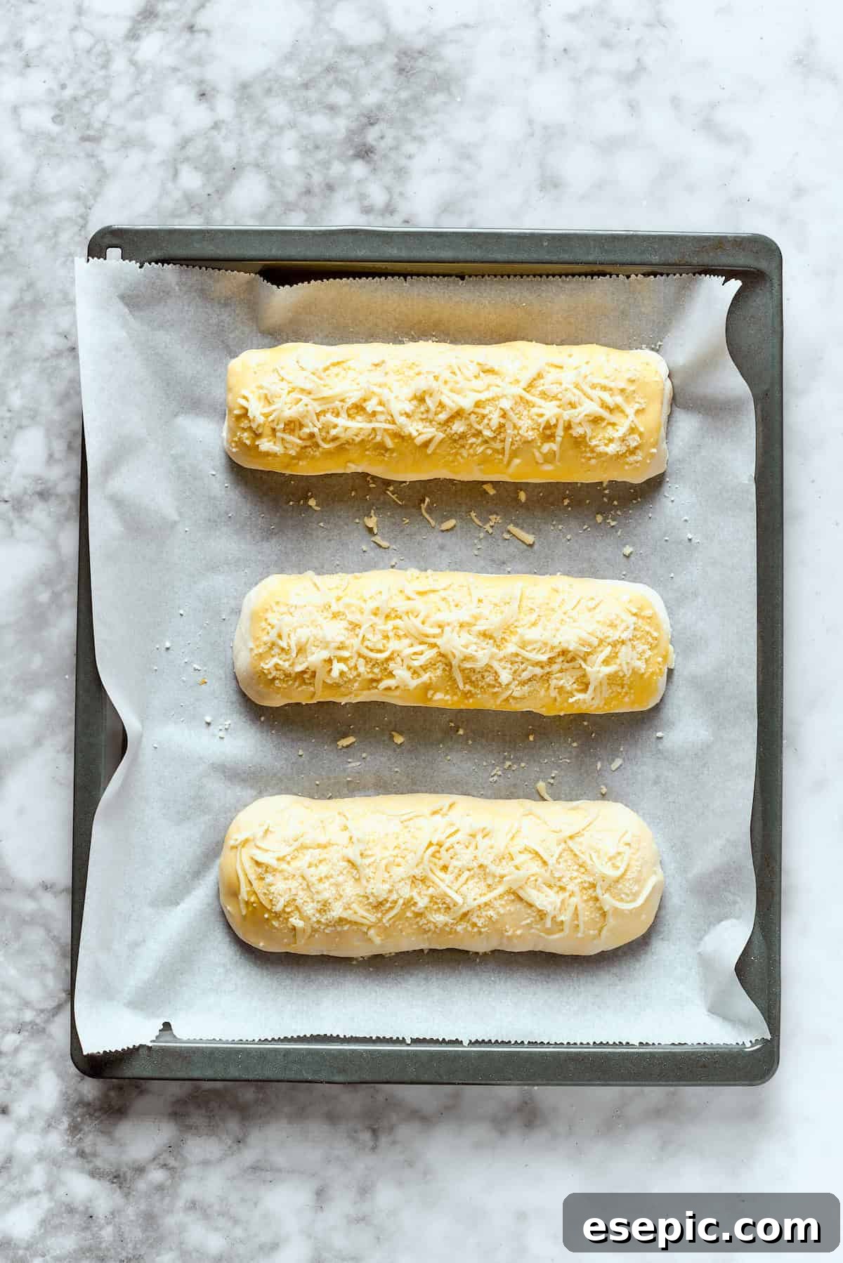 Three Costco chicken bake rolls on a baking sheet.
