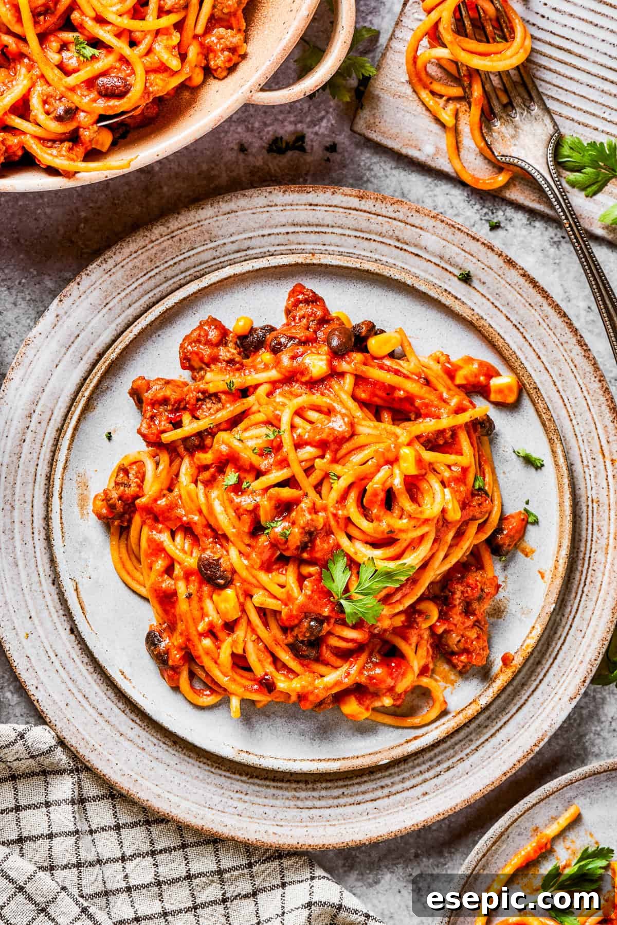 A generous serving of Mexican taco spaghetti presented on a plate, garnished with fresh cilantro and avocado slices, ready to be enjoyed.