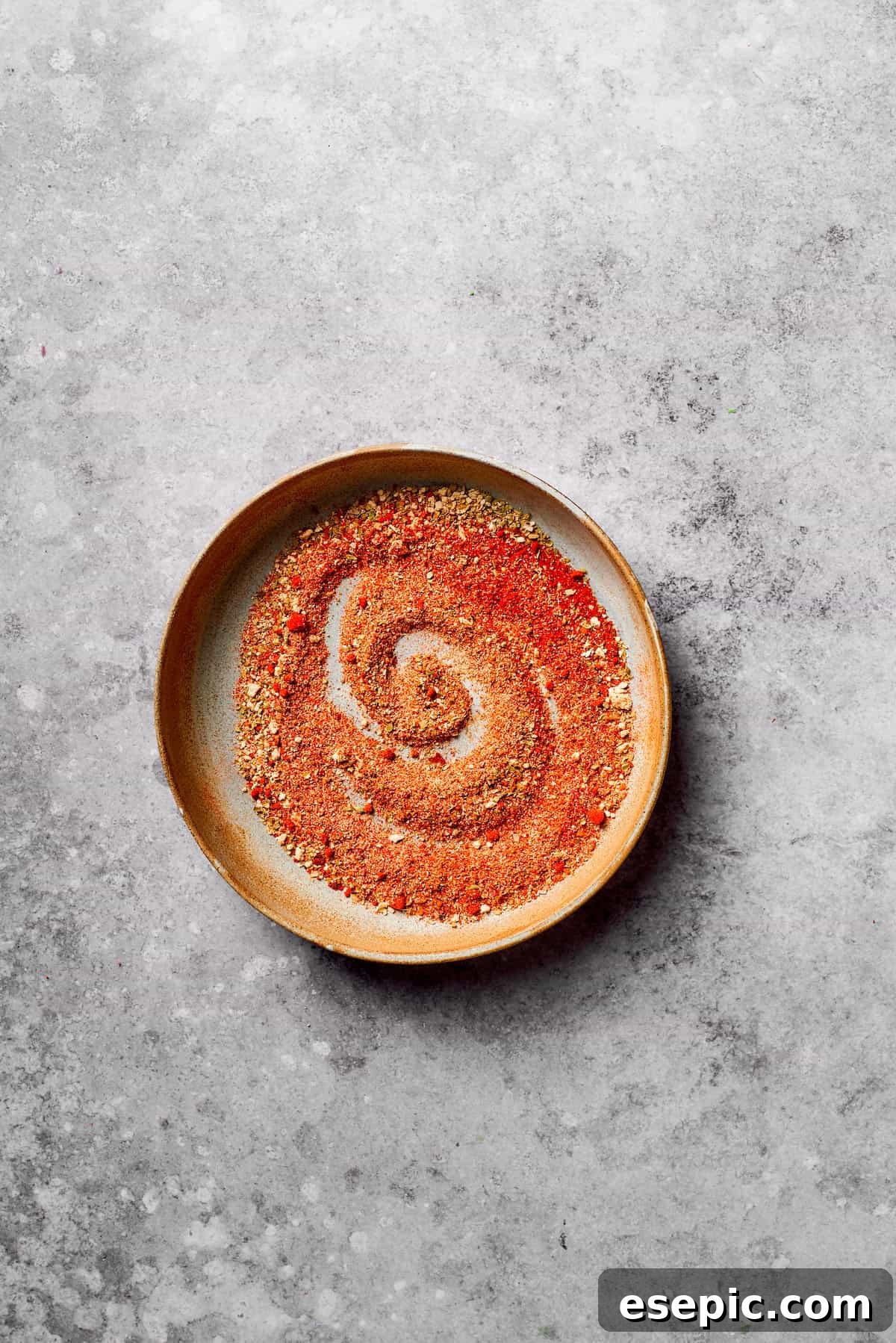 A small bowl containing a vibrant blend of ground spices, meticulously mixed for homemade taco seasoning.