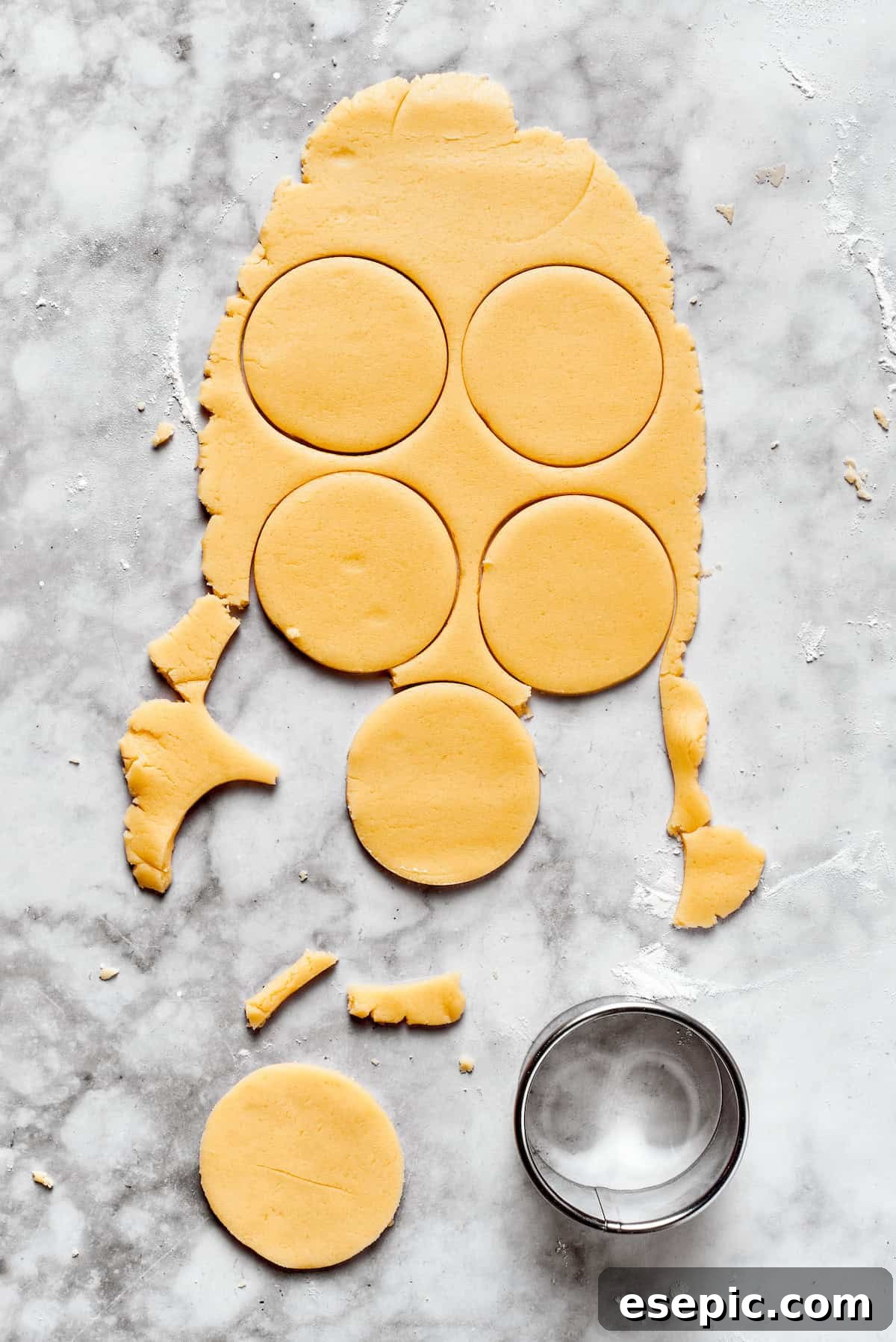 Round shapes cut from sugar cookie dough, perfectly spaced on a baking sheet.