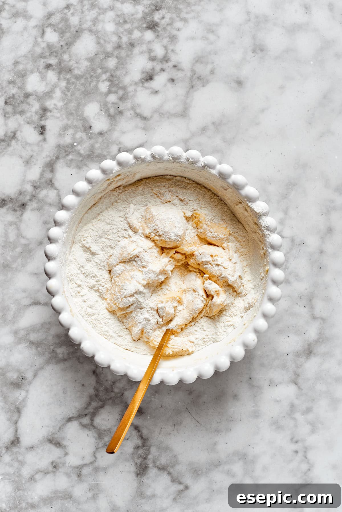 Mixing flour into cookie dough, slowly incorporating dry ingredients into the wet mixture.