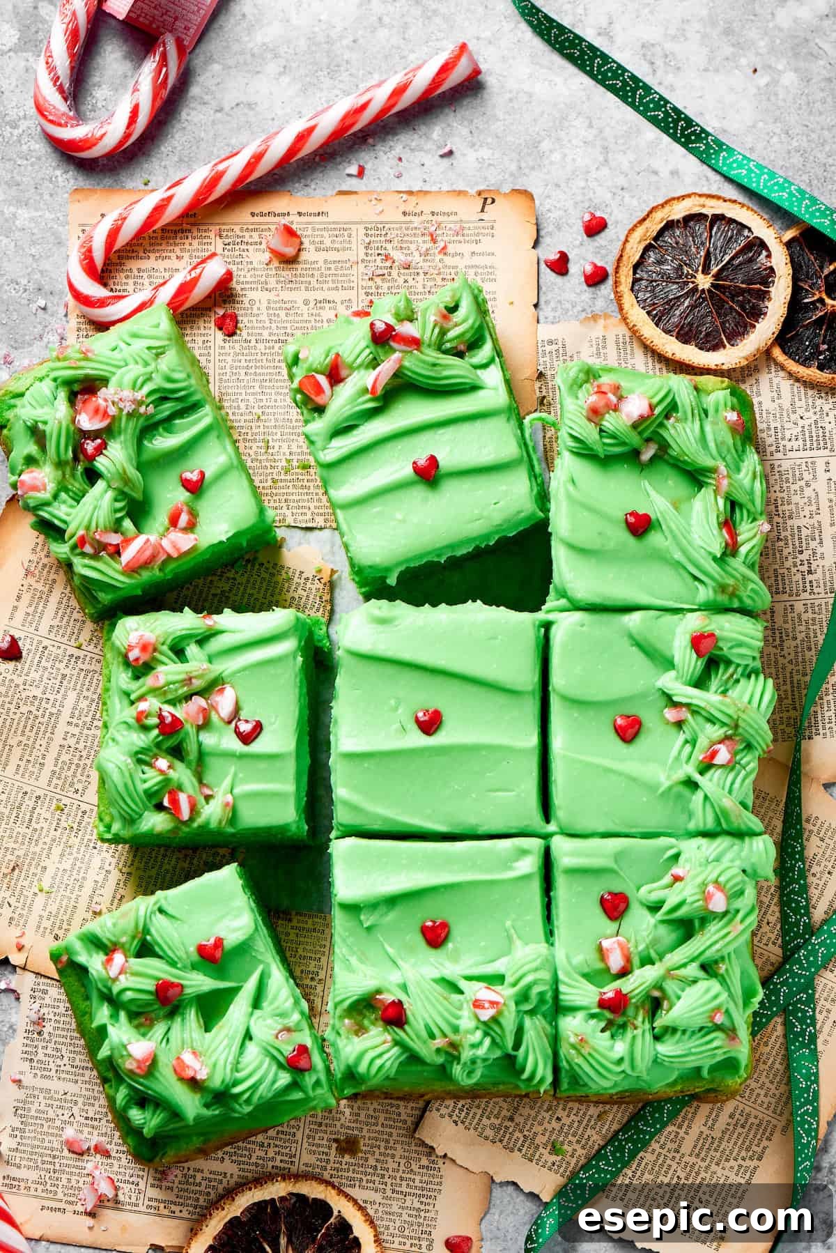 Twelve slices of grinch cake topped with candy on a counter, ready to be served at a festive holiday gathering.