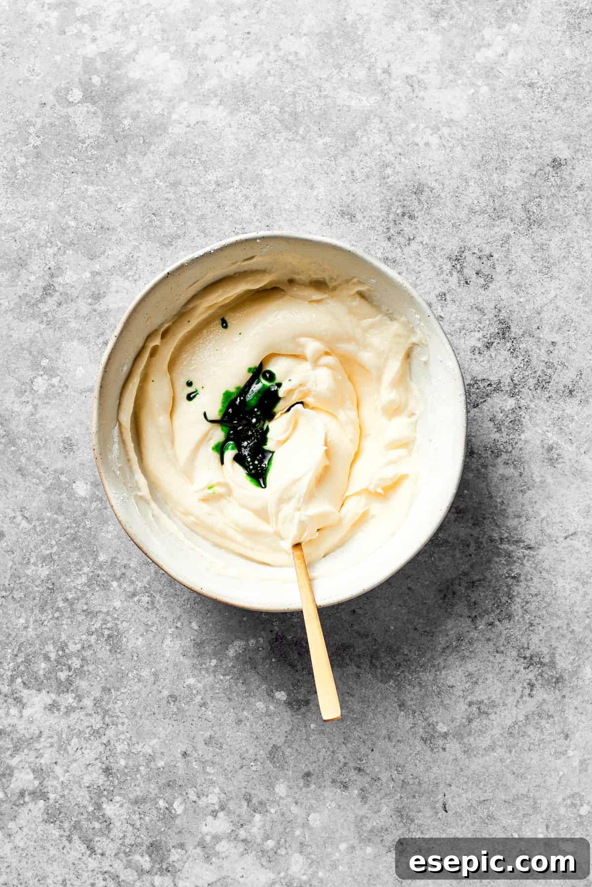 Green food coloring is added to a bowl of creamy icing, beginning the transformation.