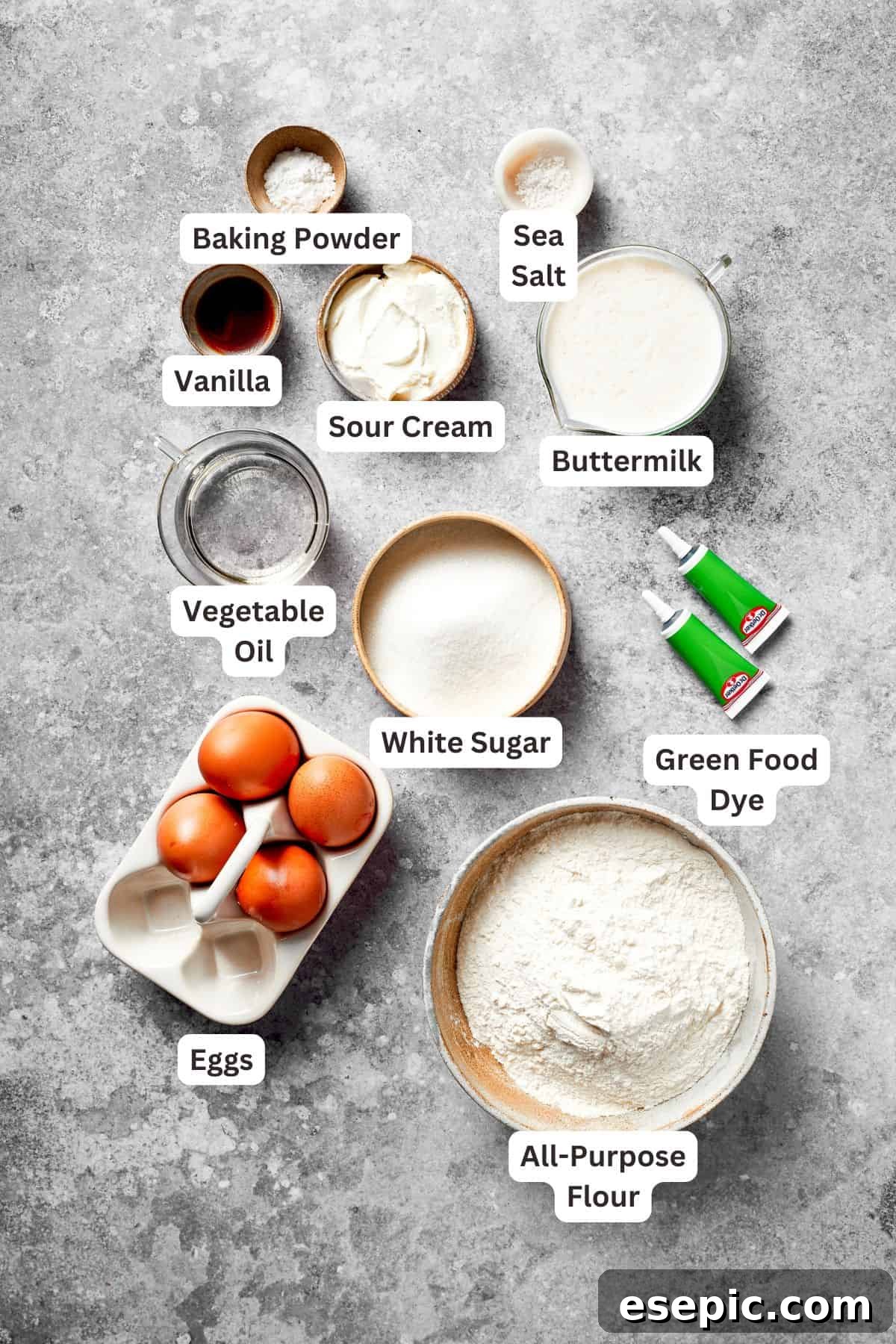 Ingredients to make a grinch cake are text labeled, laid out neatly on a kitchen counter.